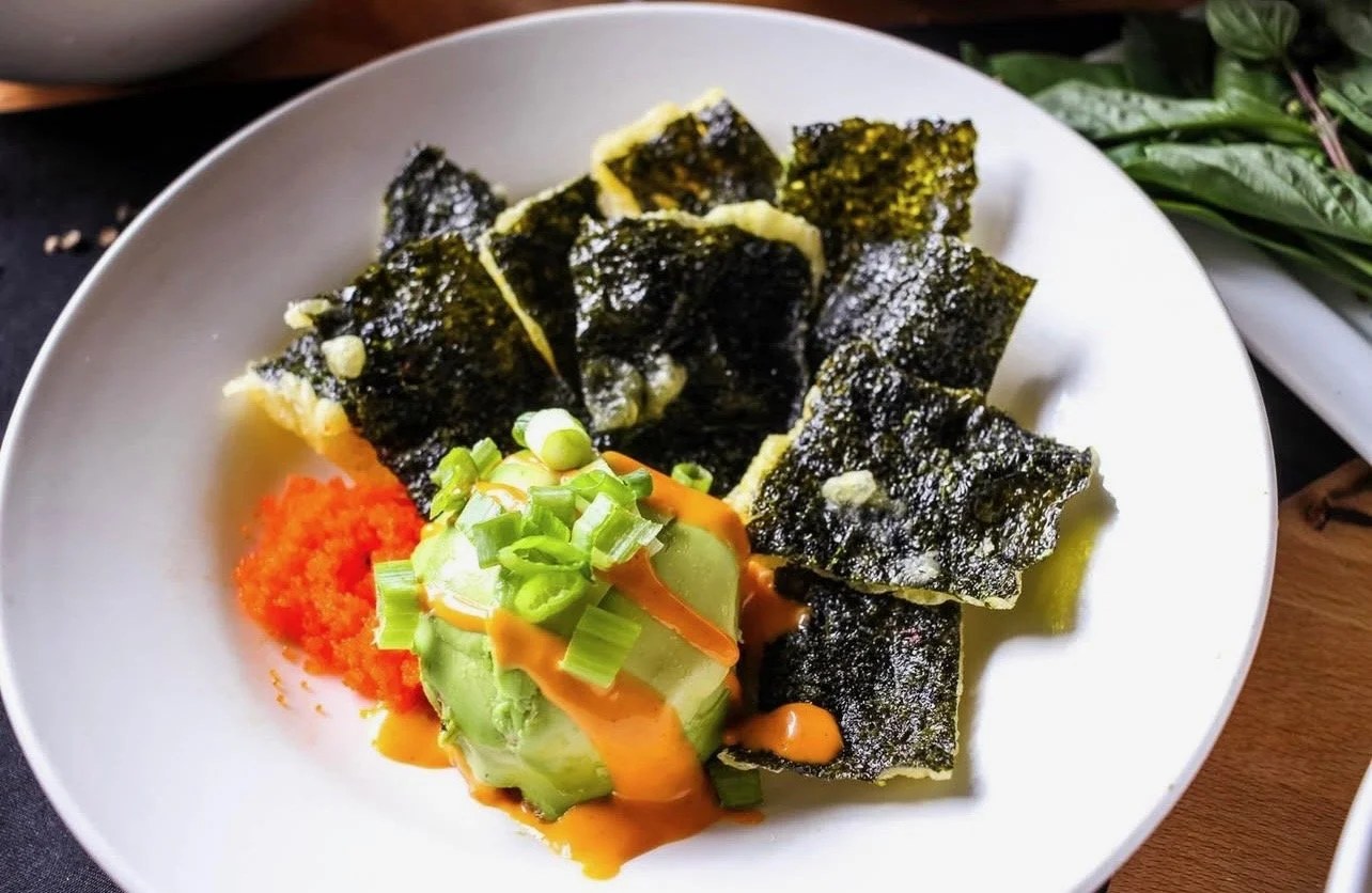 Plate of deep fried tempura seaweed chips with sliced avocado, spicy tuna, spicy aioli, and green onions.