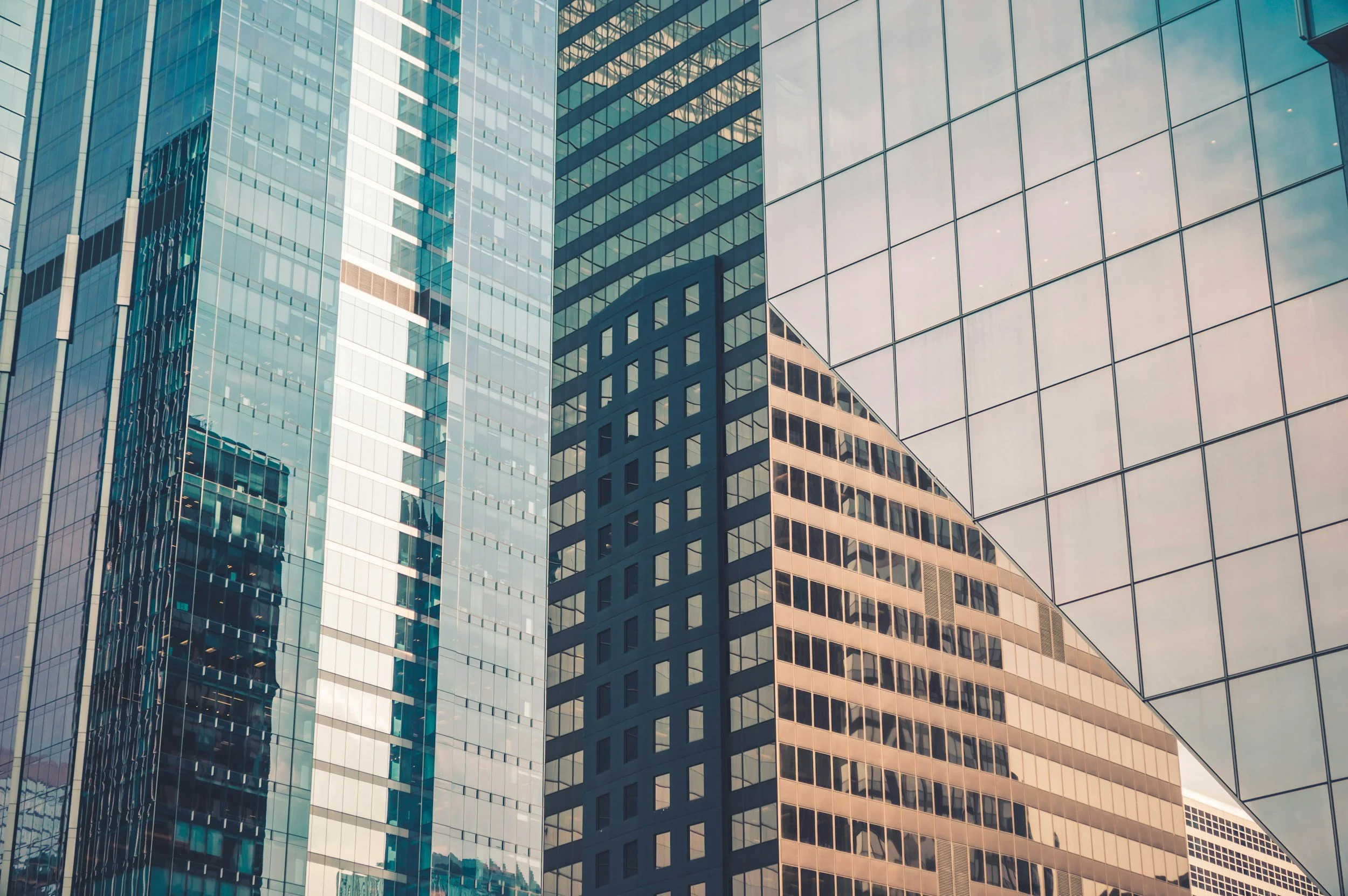 Various modern office buildings with reflective glass facades in an urban city setting.