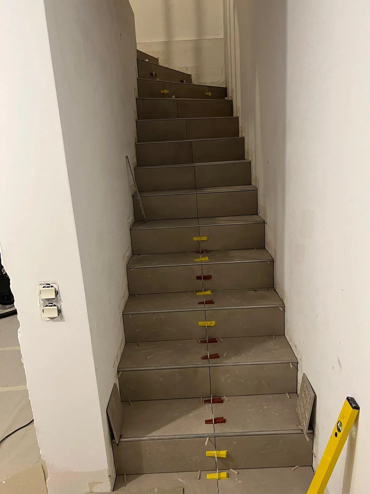 Verlegte Treppenstufen in einem Hausbau, noch unvollständig, mit Markierungen und Wasserwaage.