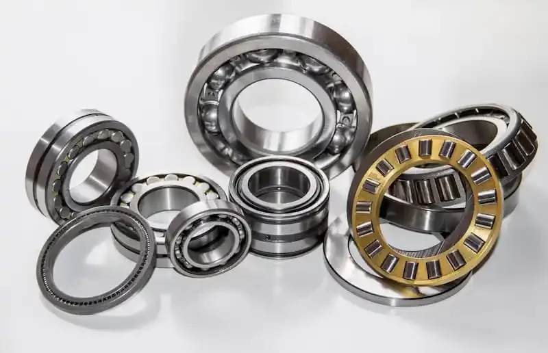 Various mechanical ball and roller bearings arranged on a white surface.