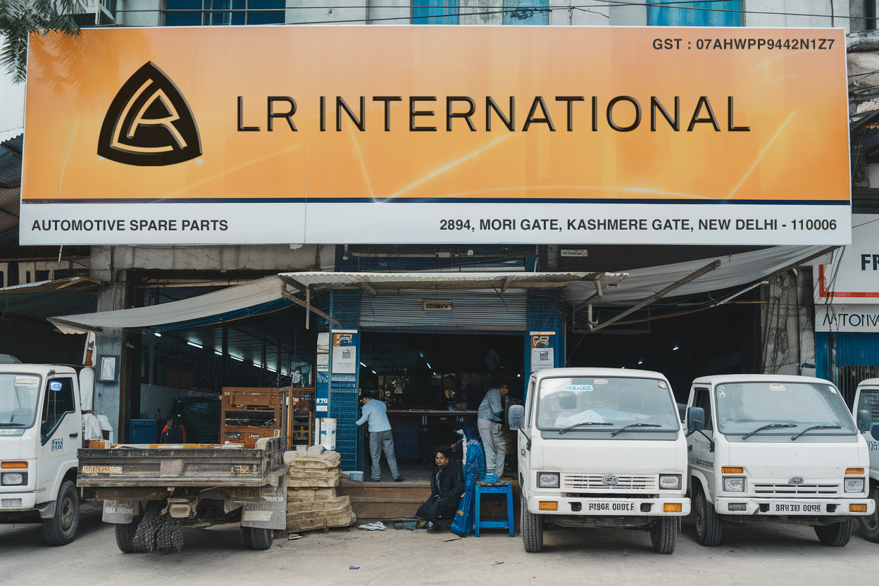 A street scene in front of an automotive spare parts store called LR International in New Delhi, India. There are three white vans parked in front of the store and a few people seated or standing near the entrance.