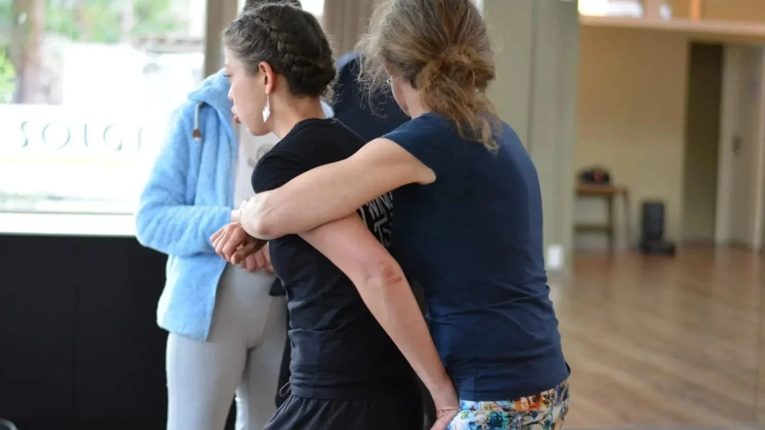Frau hilft einer verletzten jungen Frau mit Armverletzung bei einer Berührung im Raum.
