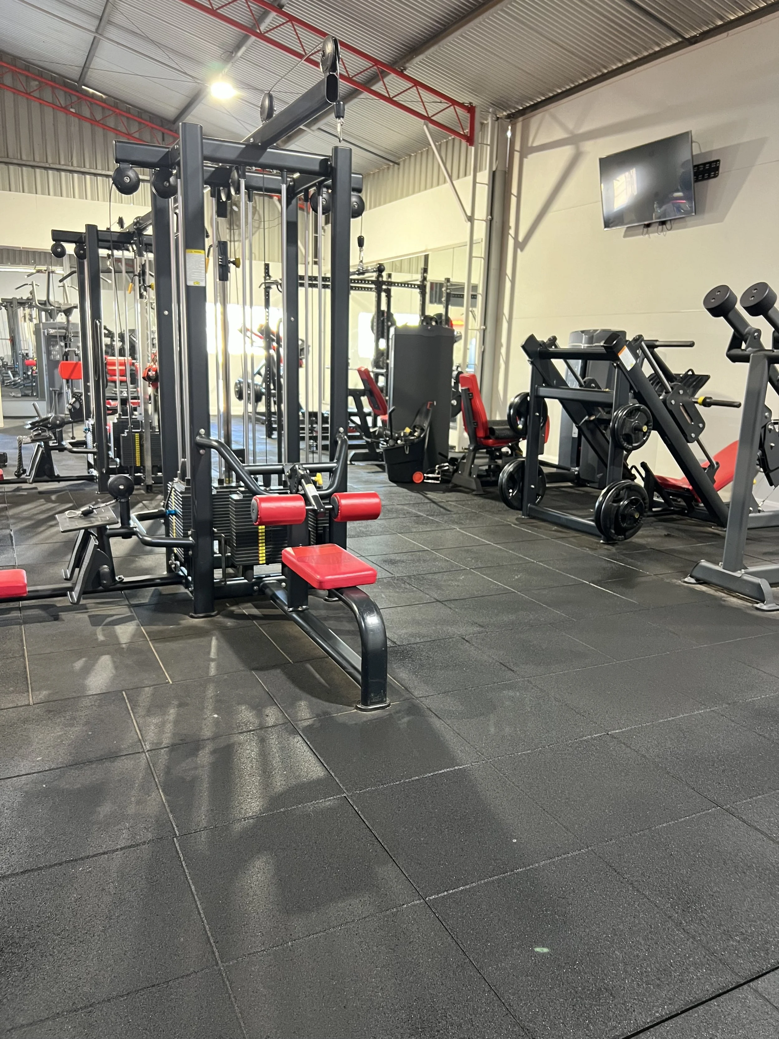 Gym cleaning Indoor gym with various exercise equipment, including weight machines and cardio equipment, on black rubber flooring.