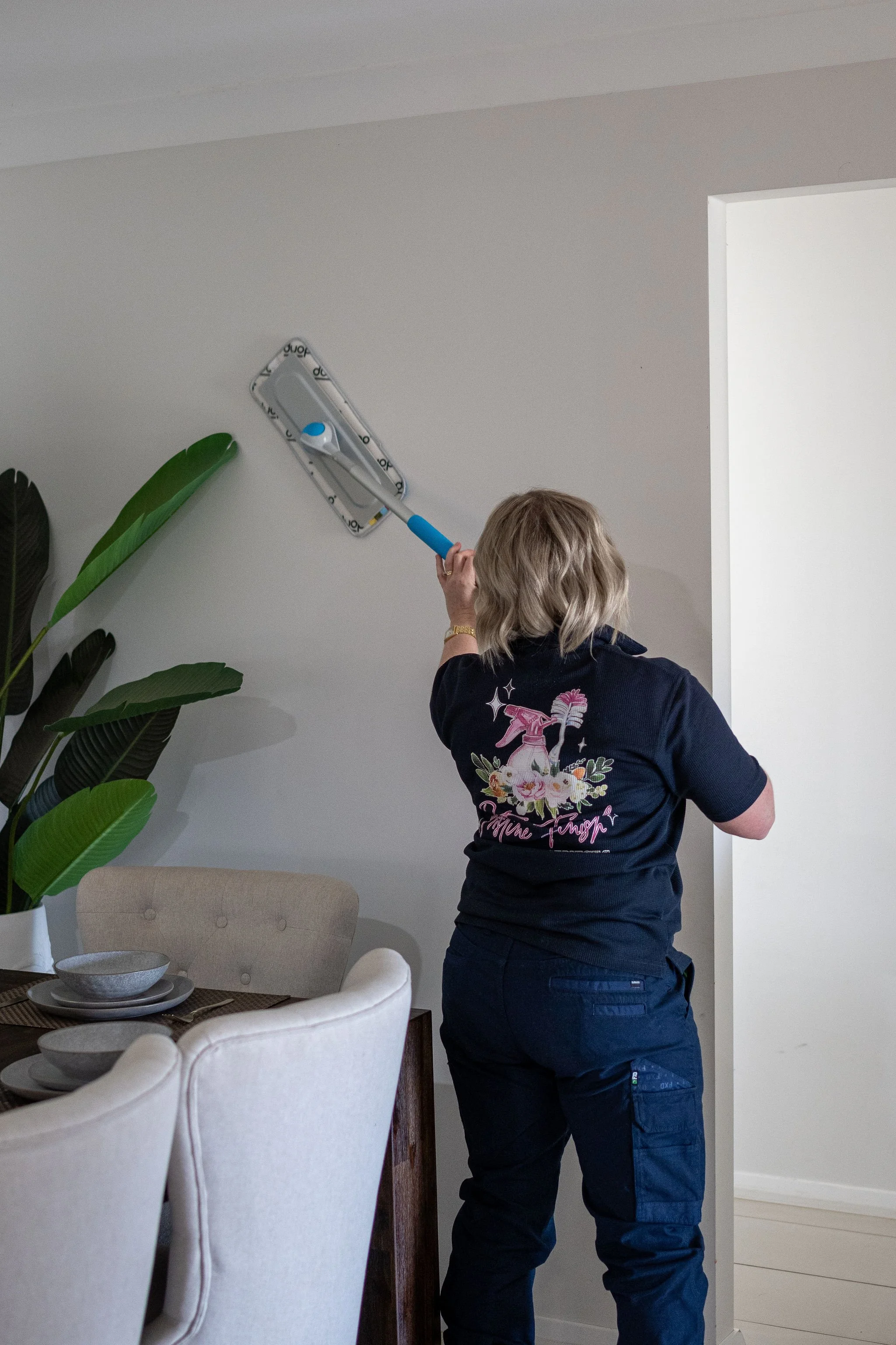 Nyngan NSW cleaning company - cleaning a ceiling with a mop in a dining room area with a plant and dining table.
