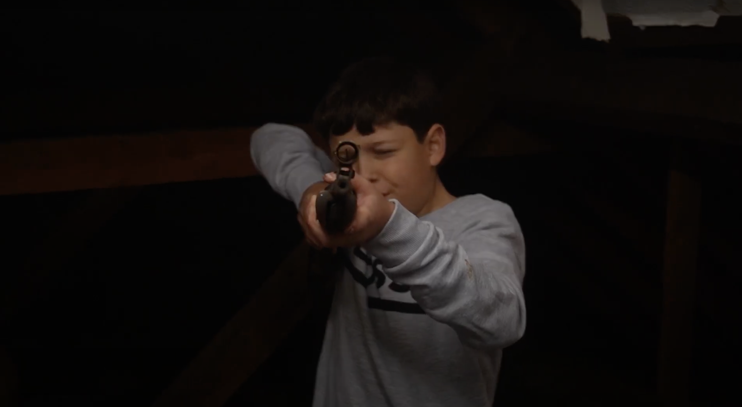 Young boy aiming a pistol in a shooting stance.