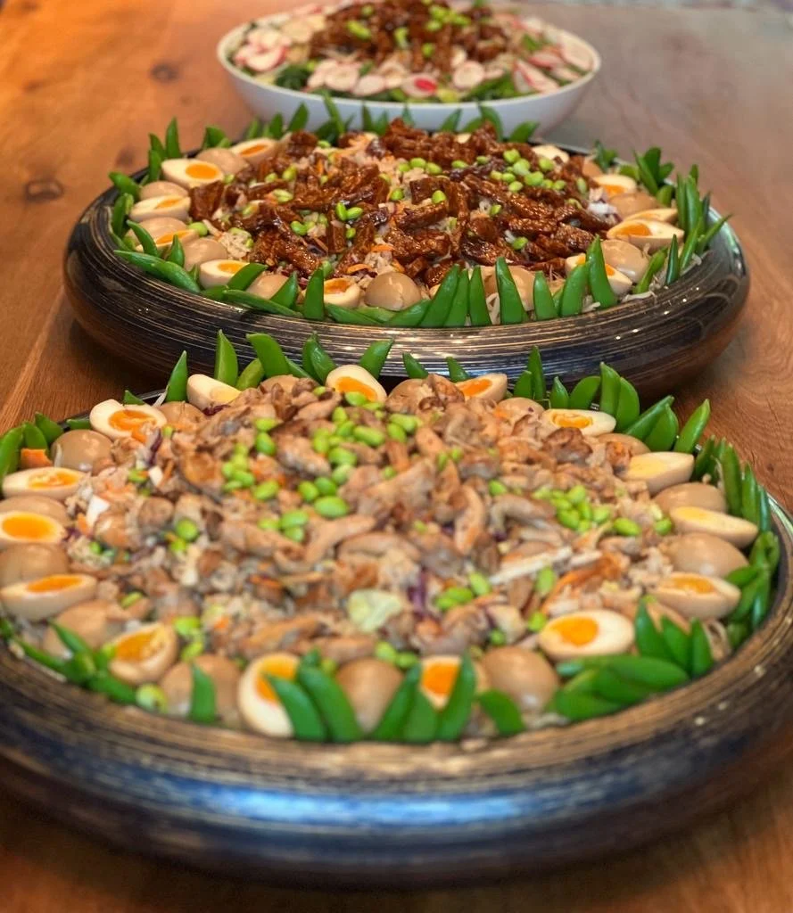 Drie grote schaaltjes met Aziatische koude gerechten met eieren, vlees, groenten en pinda's, versierd met groene uien.