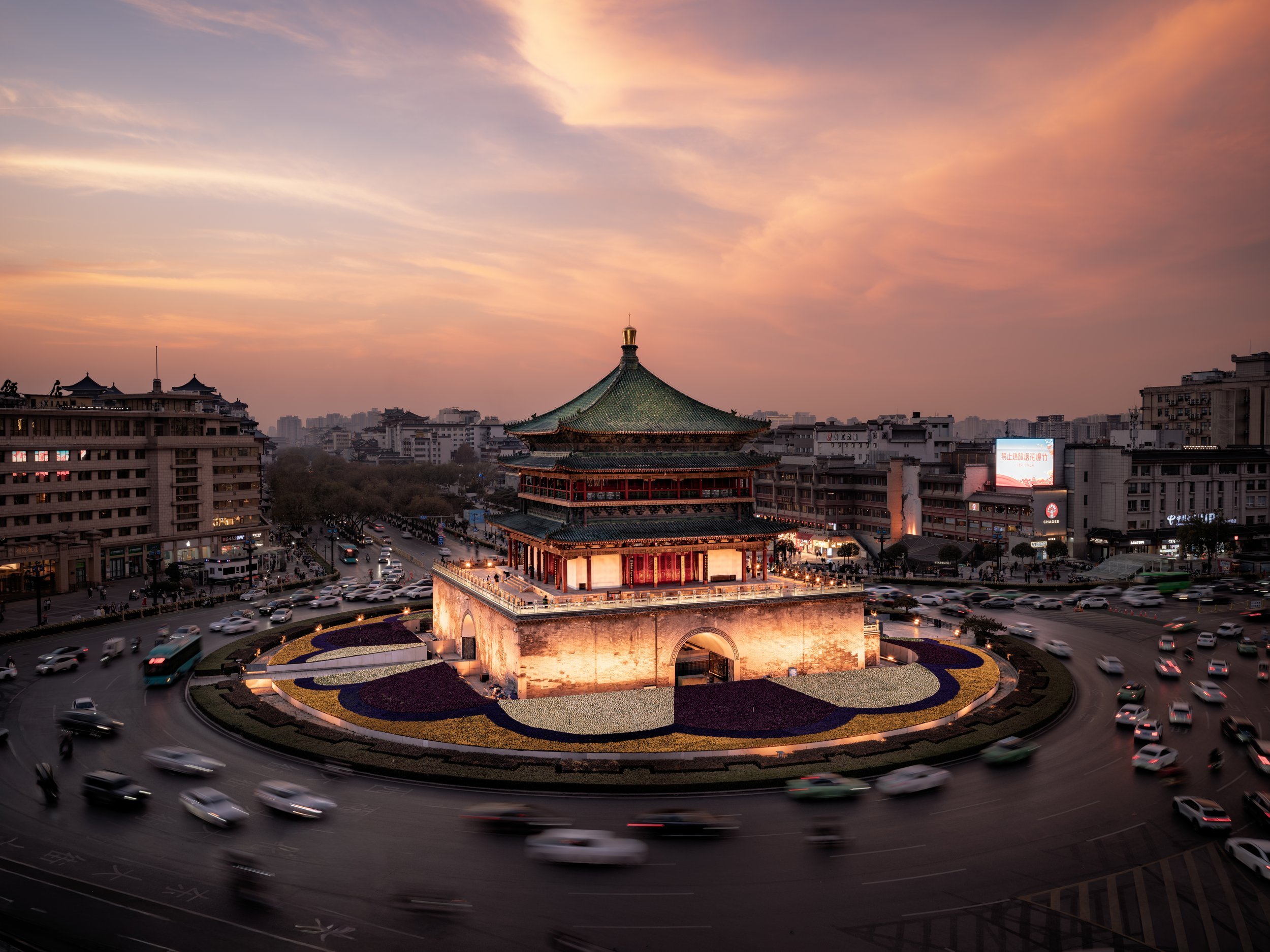 Bell Tower, Xi'an: At dusk, the Ming dynasty tower glows at the still center of the ancient capital, the evening traffic dissolving into rivers of light around it.