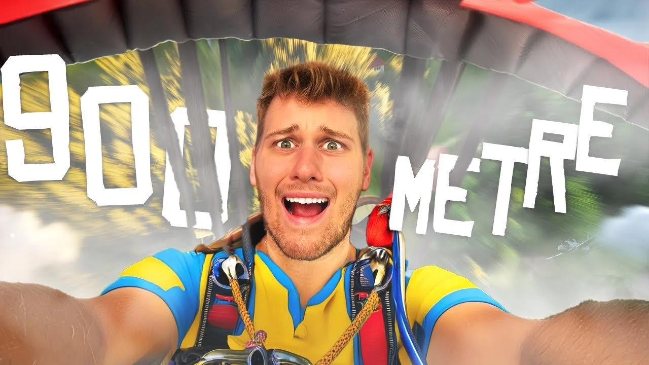 A man taking a selfie during a bungee jump. He has a surprised or scared expression, and is wearing a yellow and blue shirt with safety gear. The background shows blurred trees and sky, with the words '90 METRE' in bold white letters.