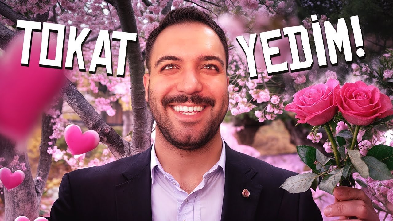 A smiling man in a suit holding pink roses standing in front of blooming pink cherry blossoms with pink hearts and the Turkish words 'TOKAT YEDİM!' written across the top.