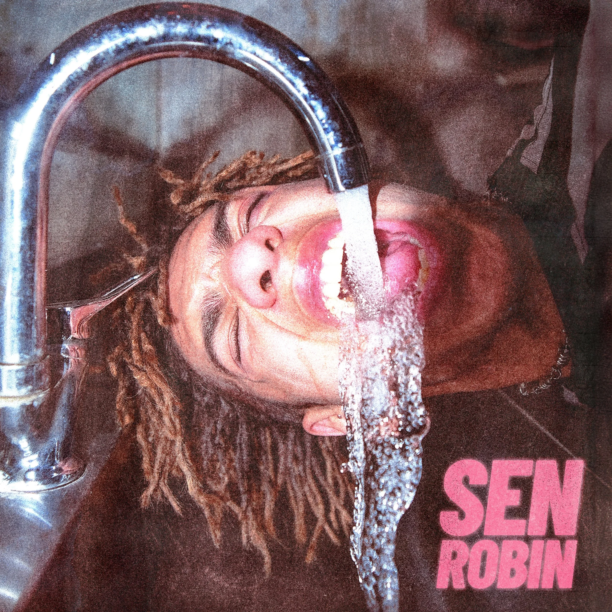 A person with dreadlocks is holding their head under a running faucet, with water streaming into their open mouth. The person is wearing a dark top, and the background includes a dark-colored surface with the words 'SEN ROBIN' in pink text.