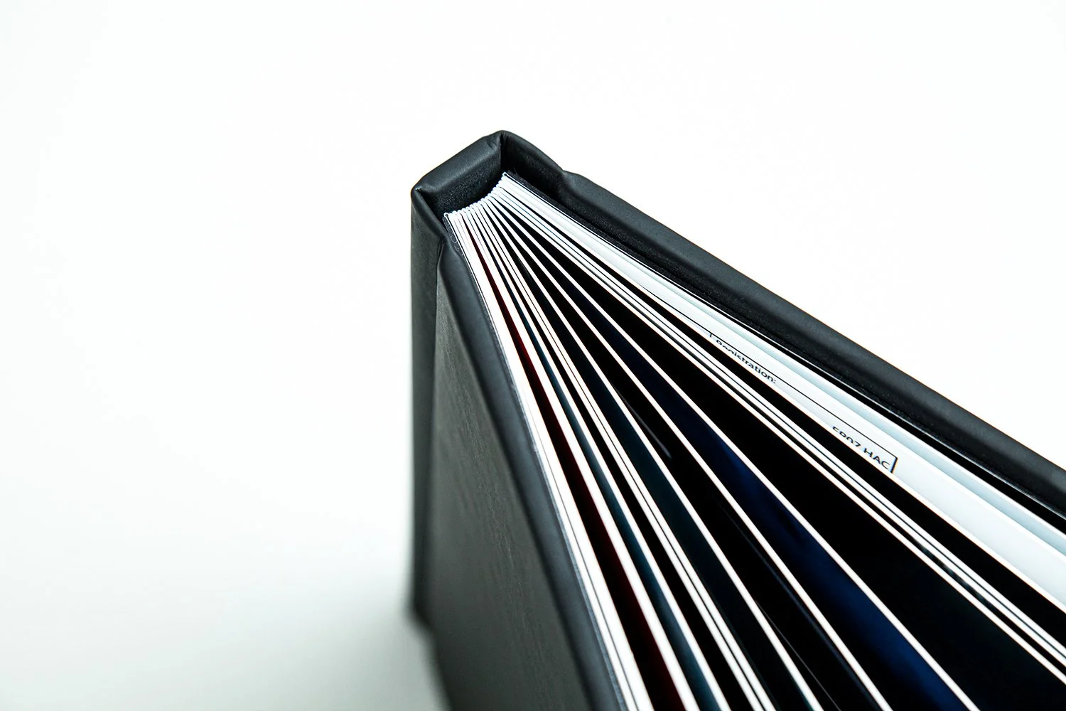 Top view of a black notebook with white and black pages, placed on a white surface.