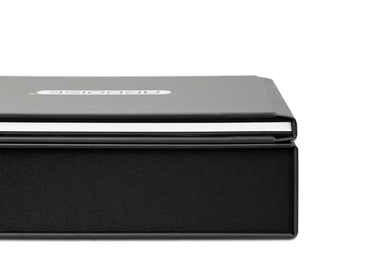 Close-up of a black hardcover journal with a grey cover and white pages, placed on a clean white background.