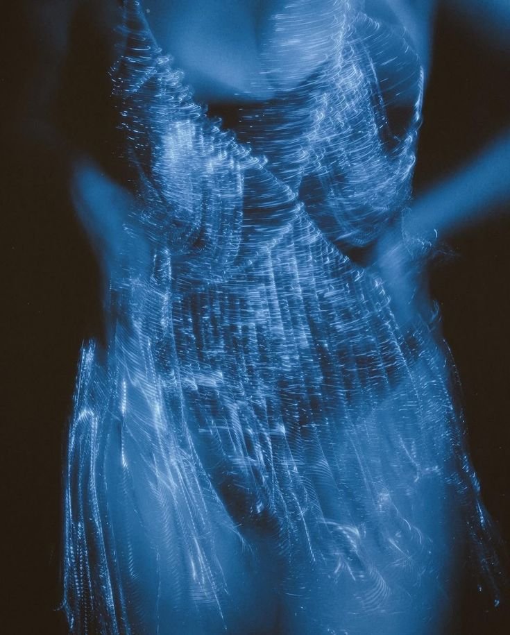 Abstract image of a person wearing a sparkling, illuminated dress against a dark background.
