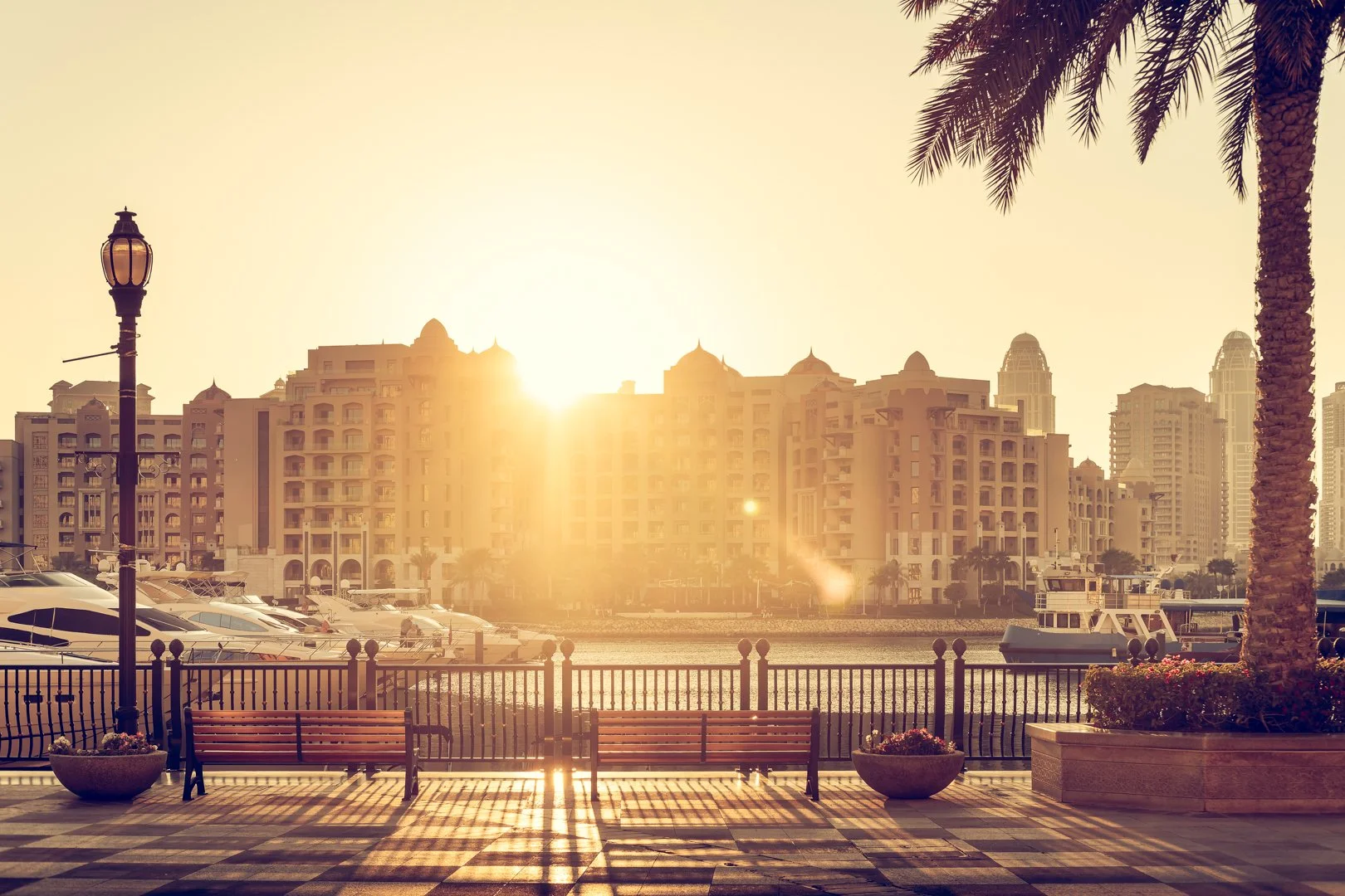 The Pearl-Qatar waterfront promenade with luxury residential towers, yachts, and marina views at sunset in Doha, Qatar