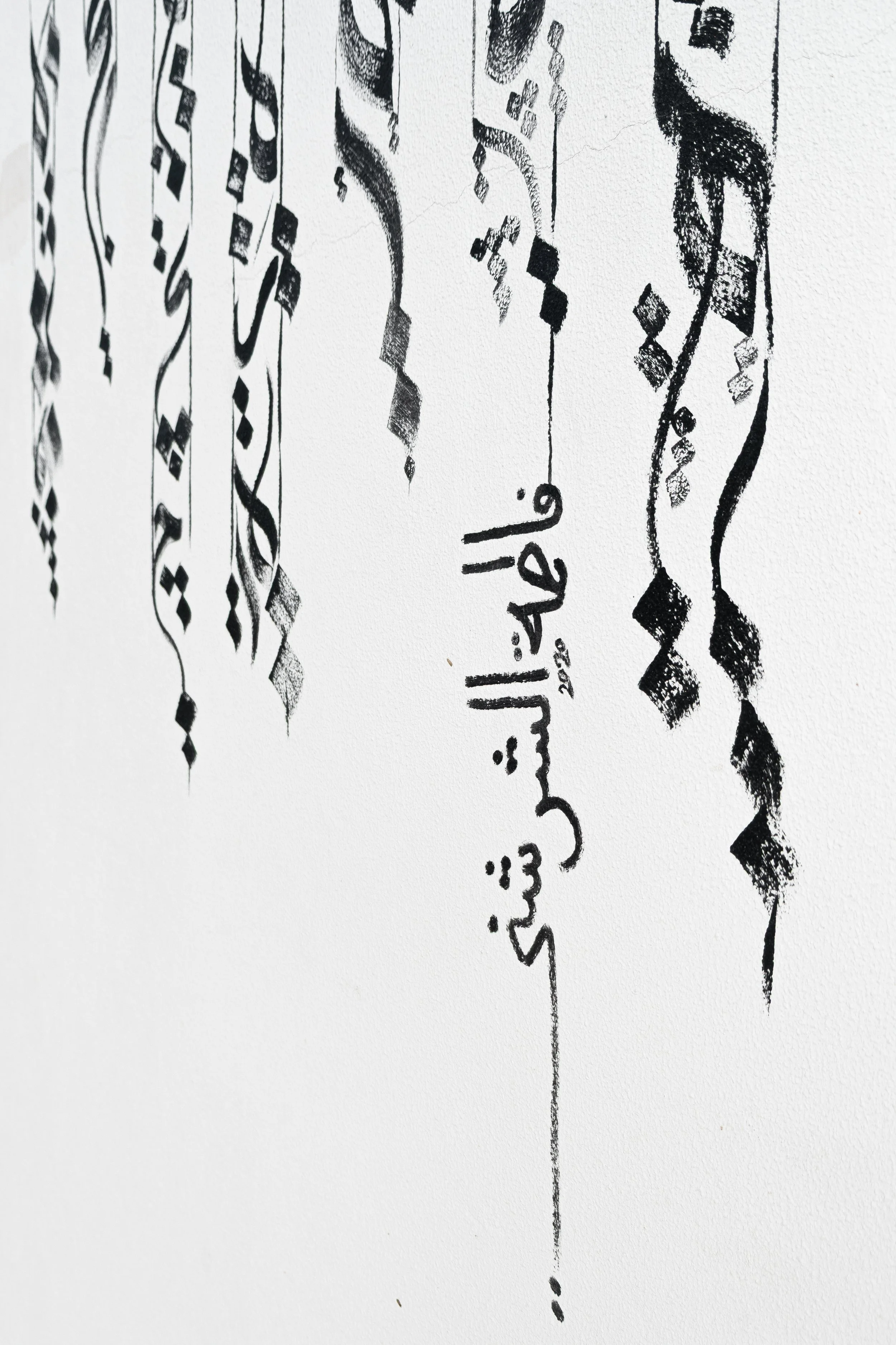 Vertical minimalist detail showing precise hand-painted Arabic calligraphy and the signature of Qatari artist Fatima Alsharshani.