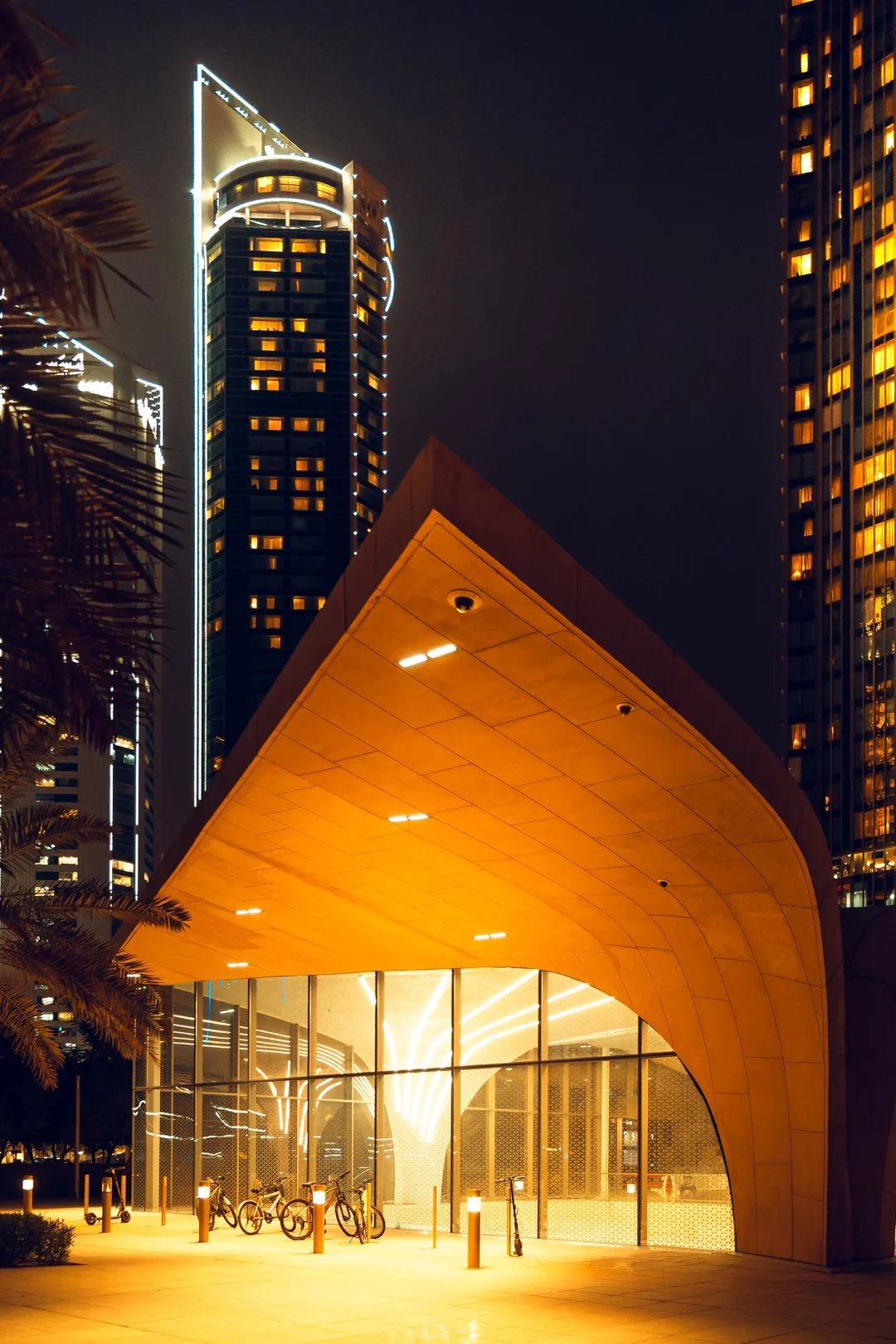 Doha Metro station entrance with modern architectural design, illuminated glass facade, and surrounding skyscrapers at night in Qatar