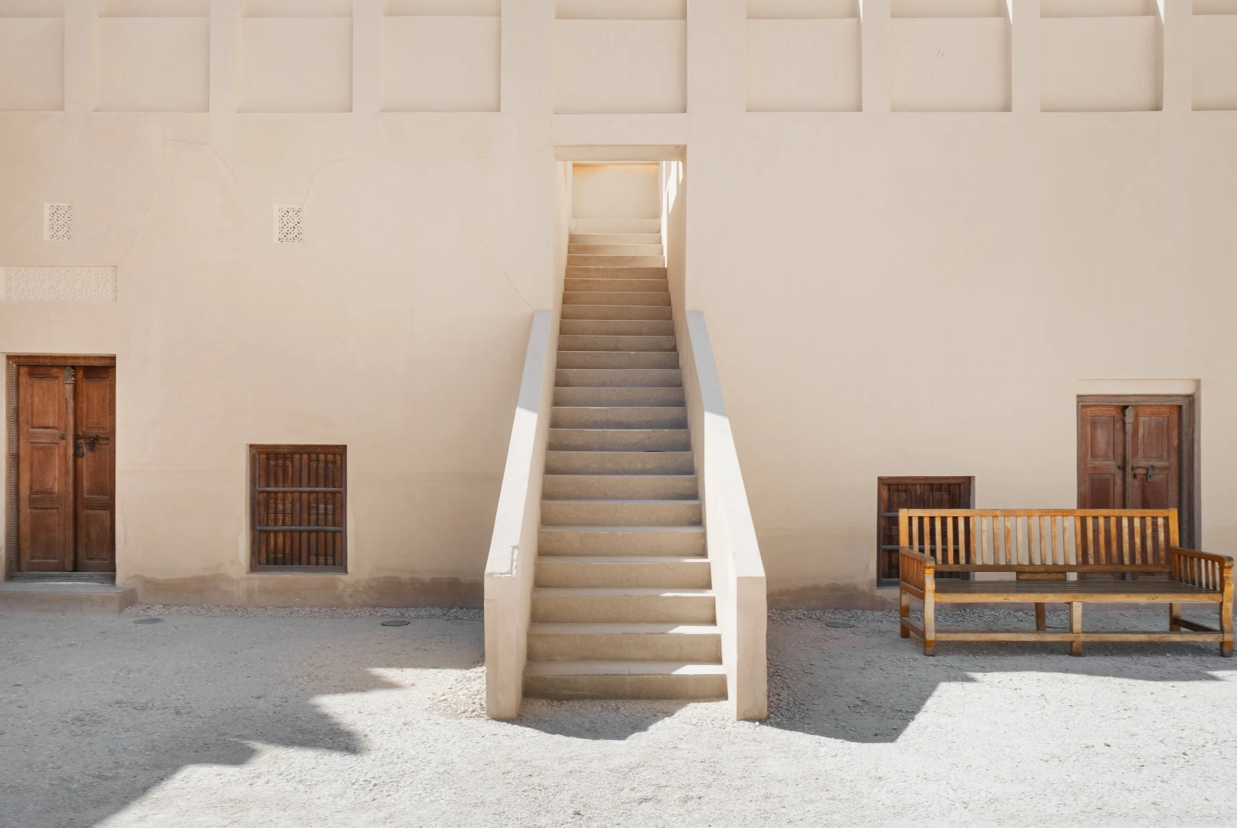 Symmetrical staircase inside the heritage palace courtyard at the National Museum of Qatar in Doha, highlighting minimalist lines, soft desert tones, and traditional architectural balance.