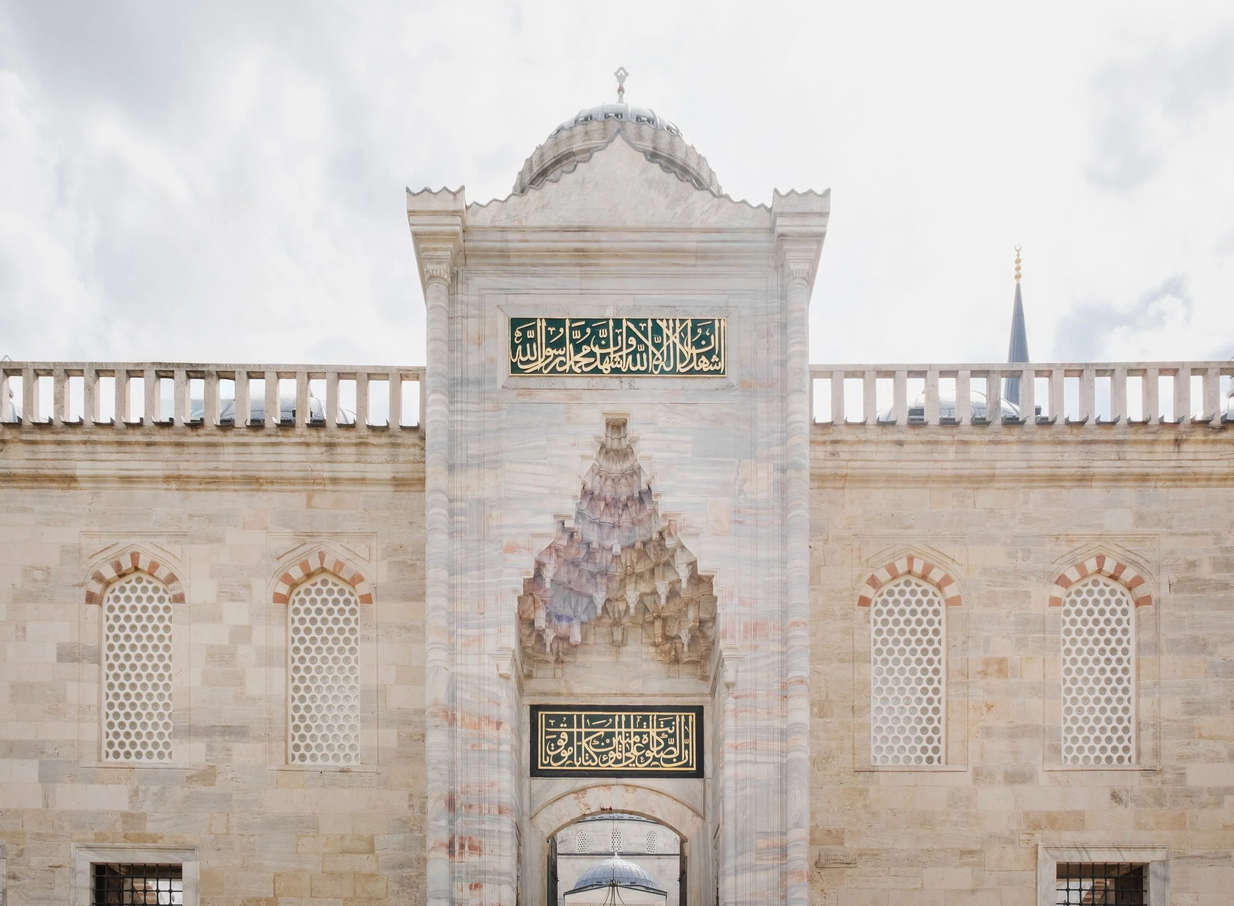 Main entrance facade of the Blue Mosque in Istanbul with Islamic calligraphy and stone carvings.