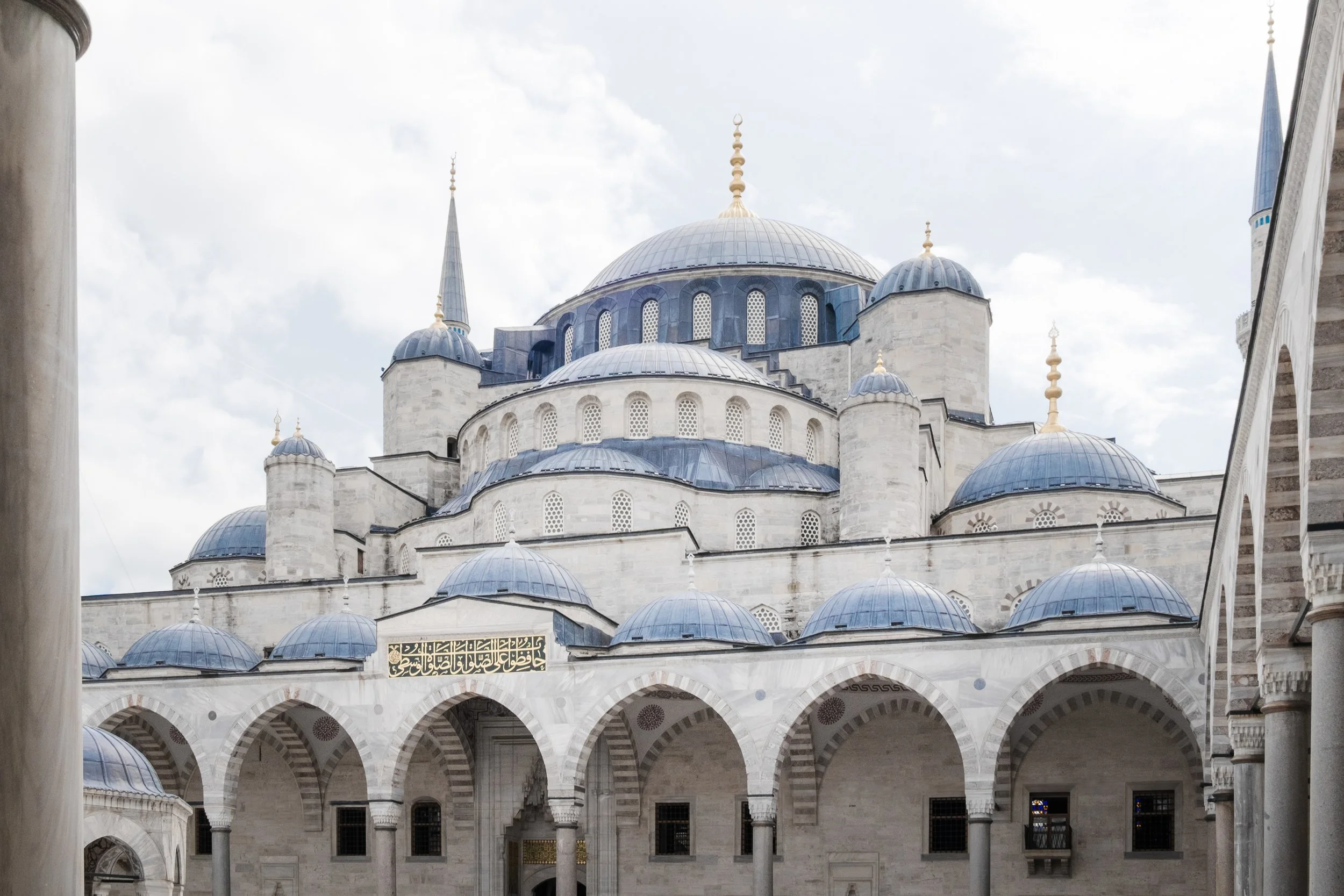 Courtyard of the Blue Mosque in Istanbul framed by domes and arches.