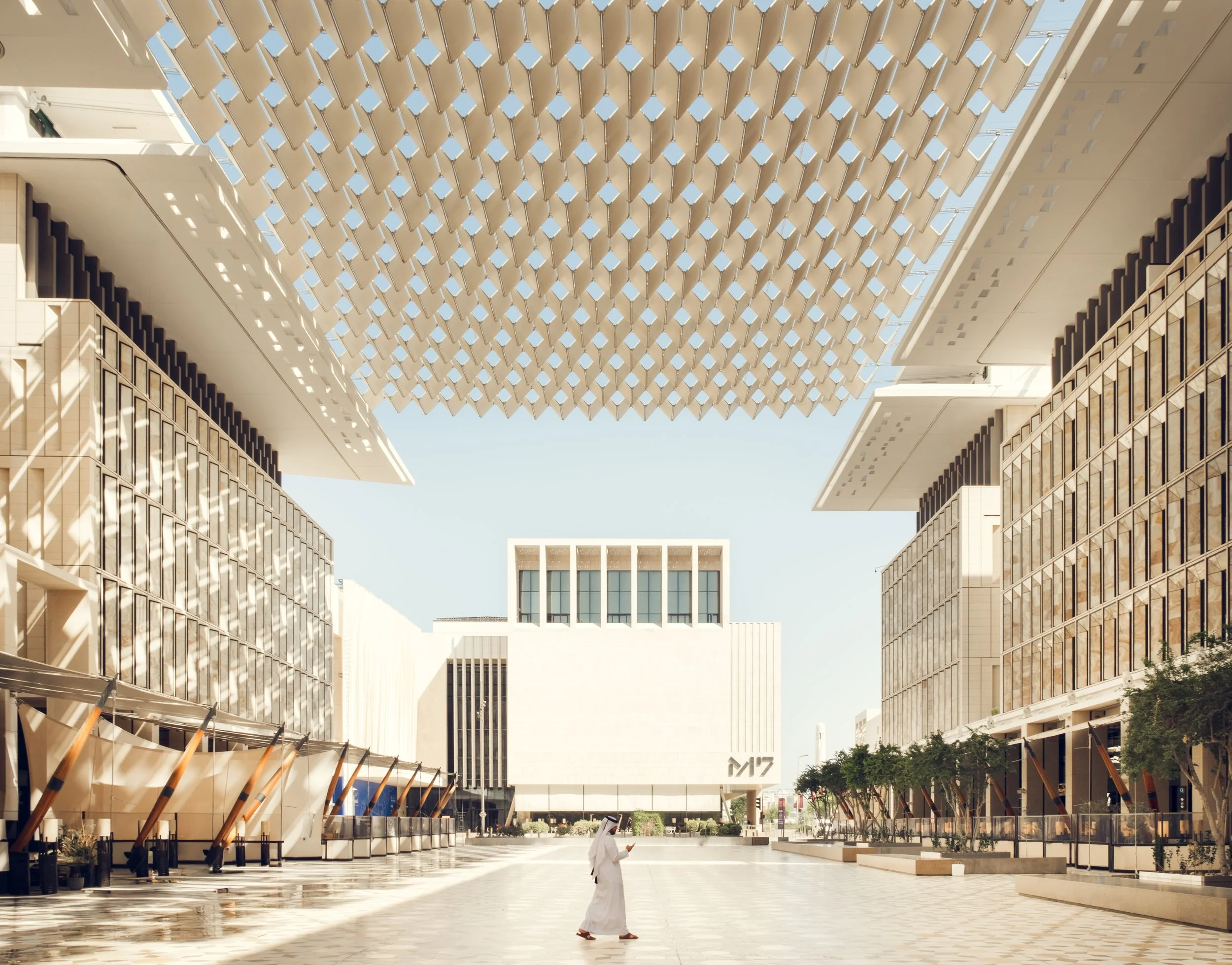 Wide view of Msheireb Downtown Doha showing contemporary urban design with a large shaded public space, geometric roof structure, and pedestrian scale architecture photographed in natural desert light.
