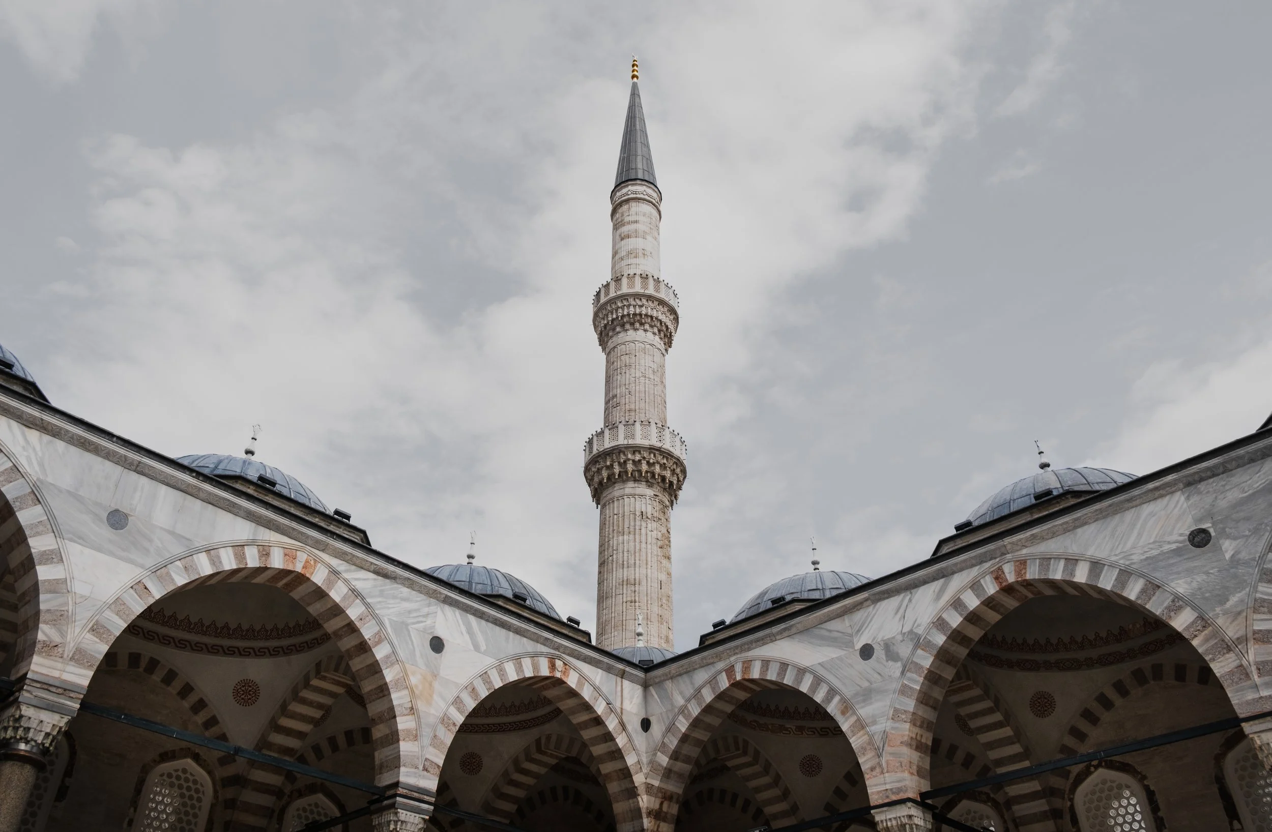 Stone arches in the courtyard of the Blue Mosque in Istanbul with minaret view.