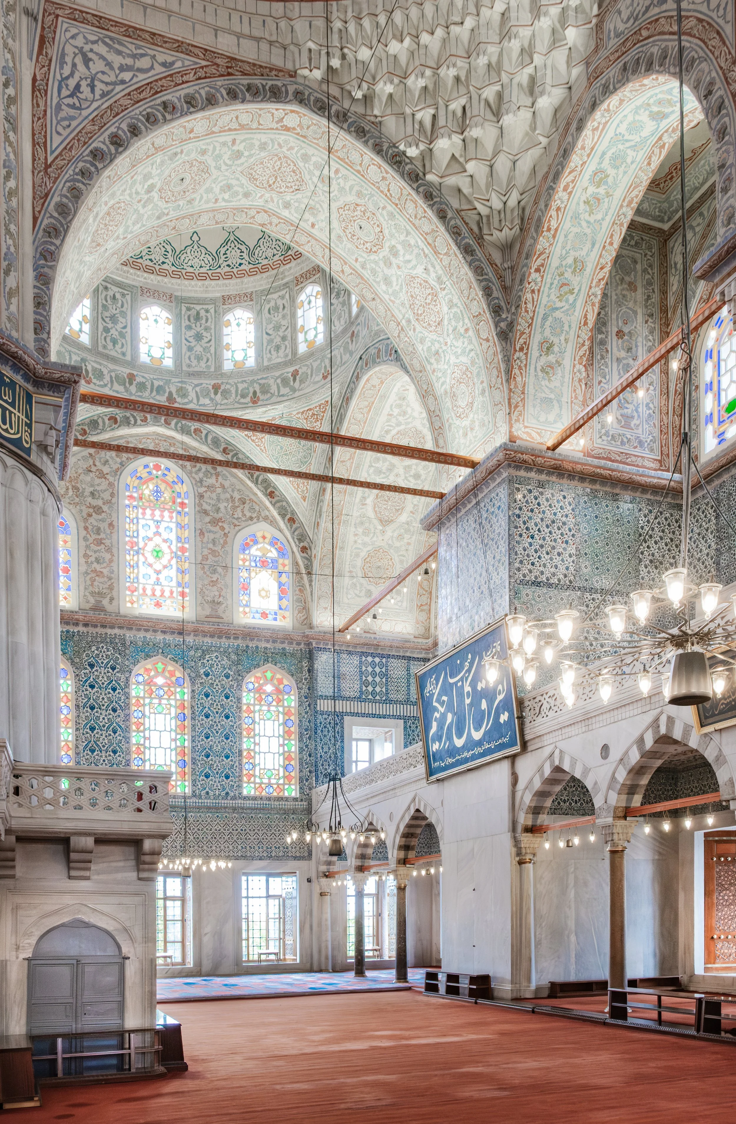 Interior arches and stained glass windows decorated with tiles in the Blue Mosque in Istanbul.
