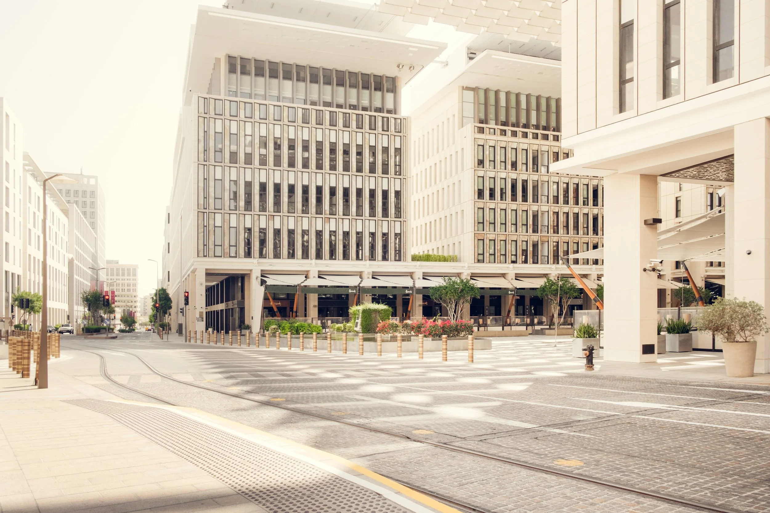 Urban intersection in Msheireb Downtown Doha showing contemporary architecture, integrated public space, pedestrian oriented streetscape, and cohesive urban scale photographed in natural daylight.