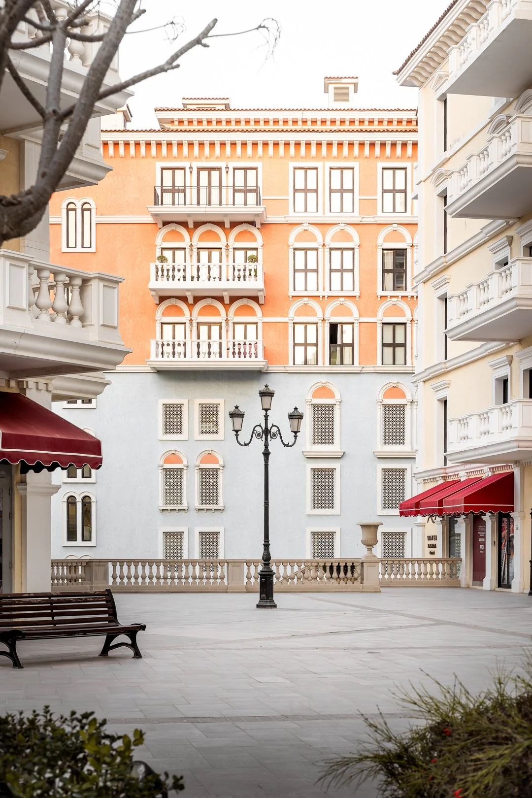 Qanat Quartier square with pastel buildings, red awnings, and a central street lamp, European-style architecture in Doha.
