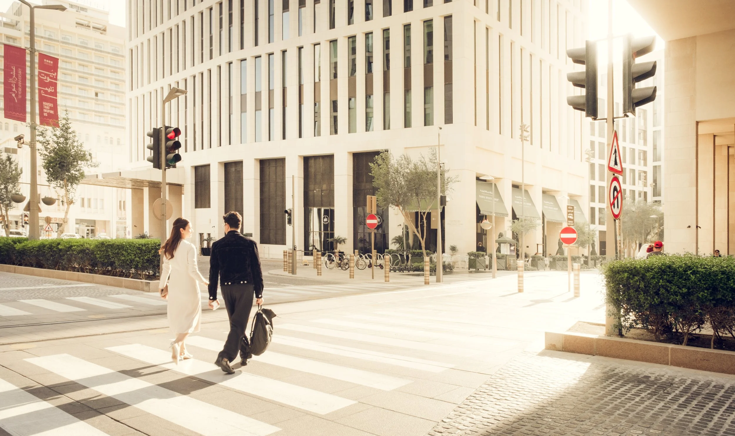Pedestrians crossing a street in Msheireb Downtown Doha illustrating human scale urban design, contemporary architecture, and walkable streetscape captured in soft natural daylight.