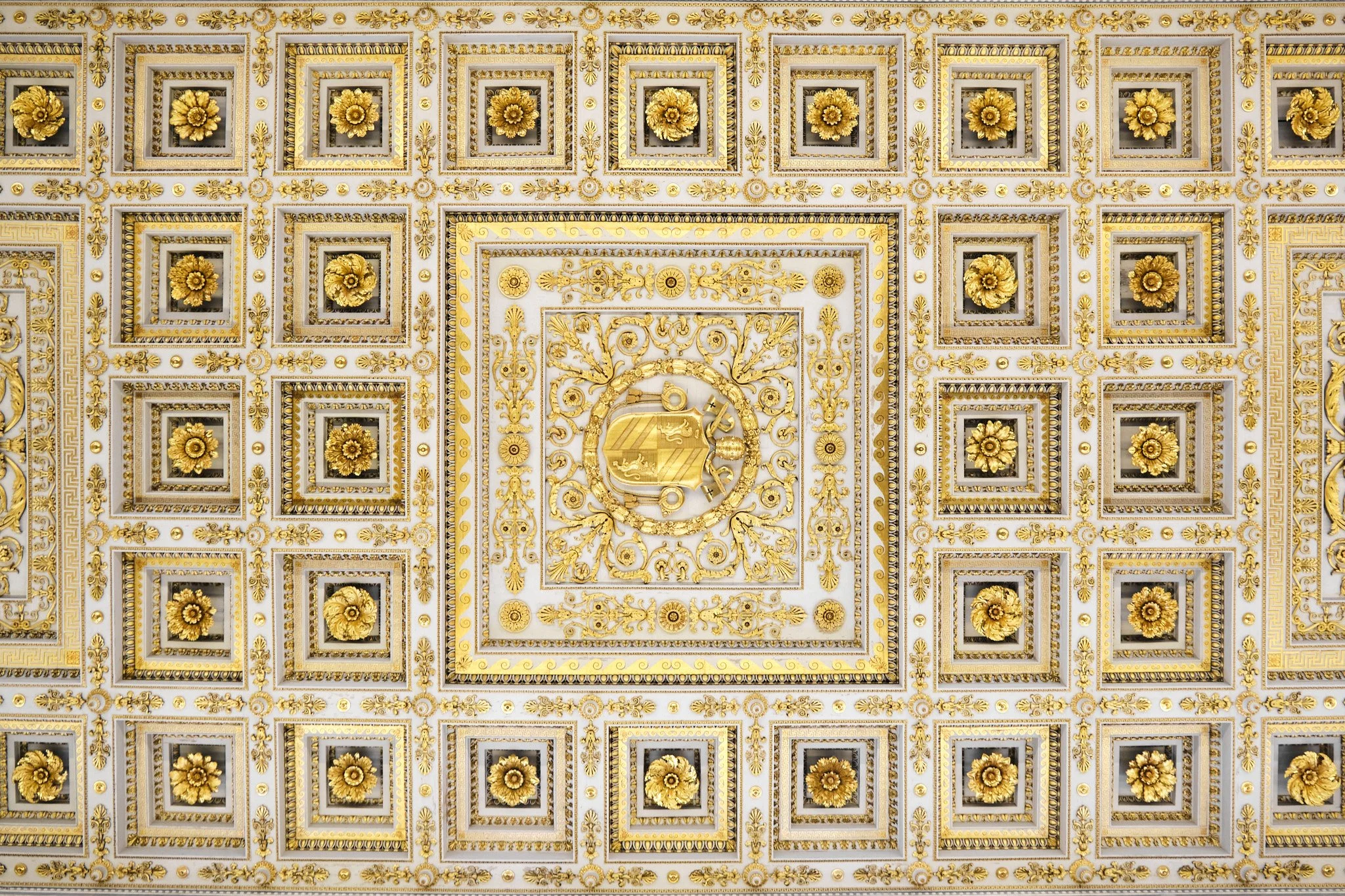 Looking straight up at the white and gold coffered ceiling panels of the Basilica di San Paolo Fuori le Mura, geometric repetition in natural light.