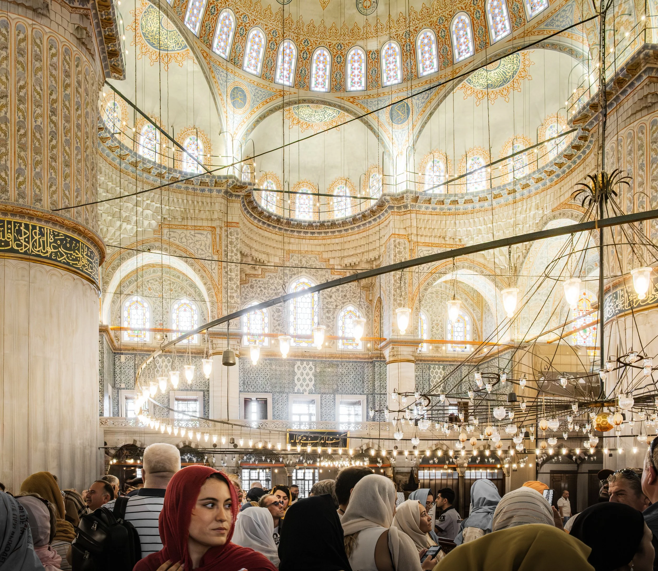 Wide ceiling view of painted domes and arches inside the Blue Mosque in Istanbul.
