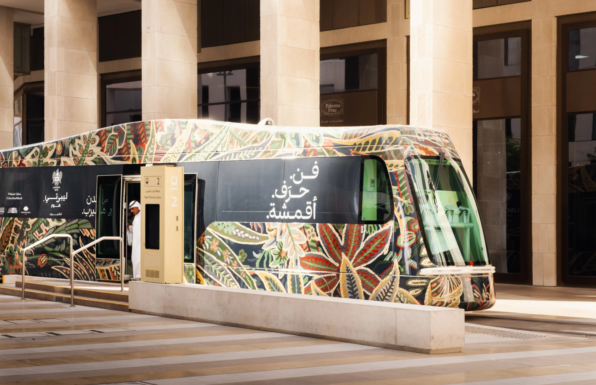 Modern tram stopped in Msheireb Downtown Doha highlighting integrated public transport, patterned graphic design, contemporary architecture, and pedestrian oriented urban planning.