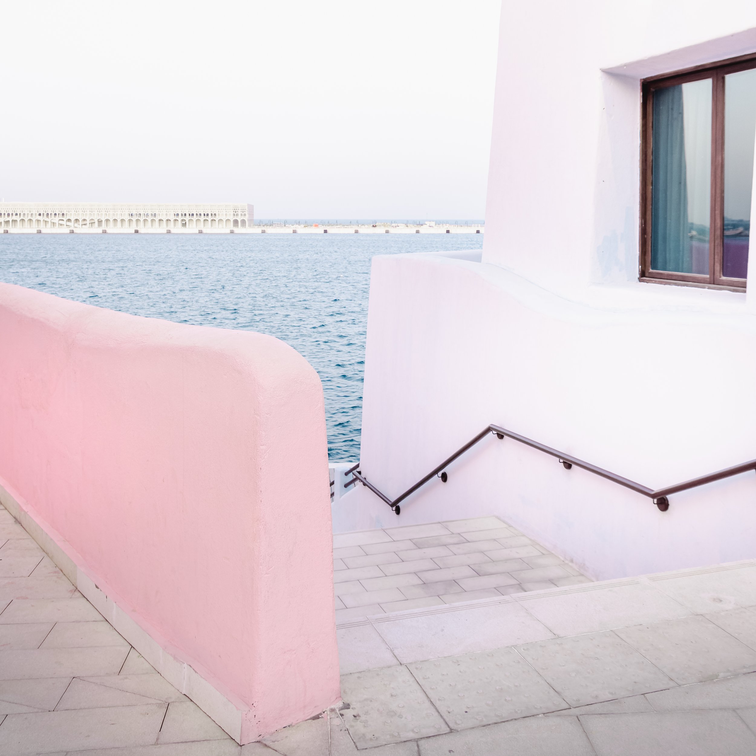 Sea wall contrasts with Doha’s vertical skyline, fits perfectly with your “horizontal living vs towers” argument.