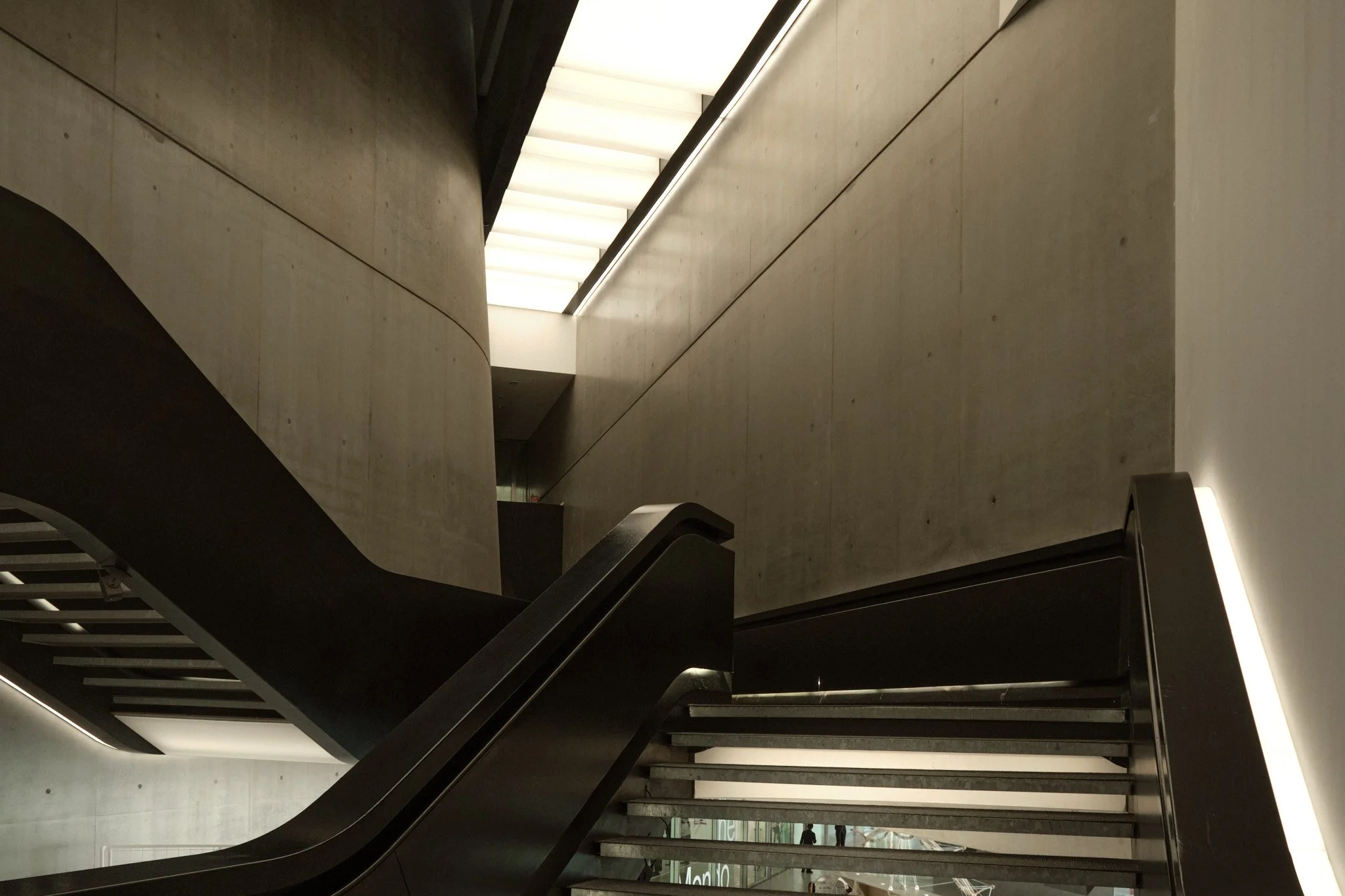 Staircase landing at MAXXI Rome in black and white, concrete surfaces and controlled light defining the spatial boundary.