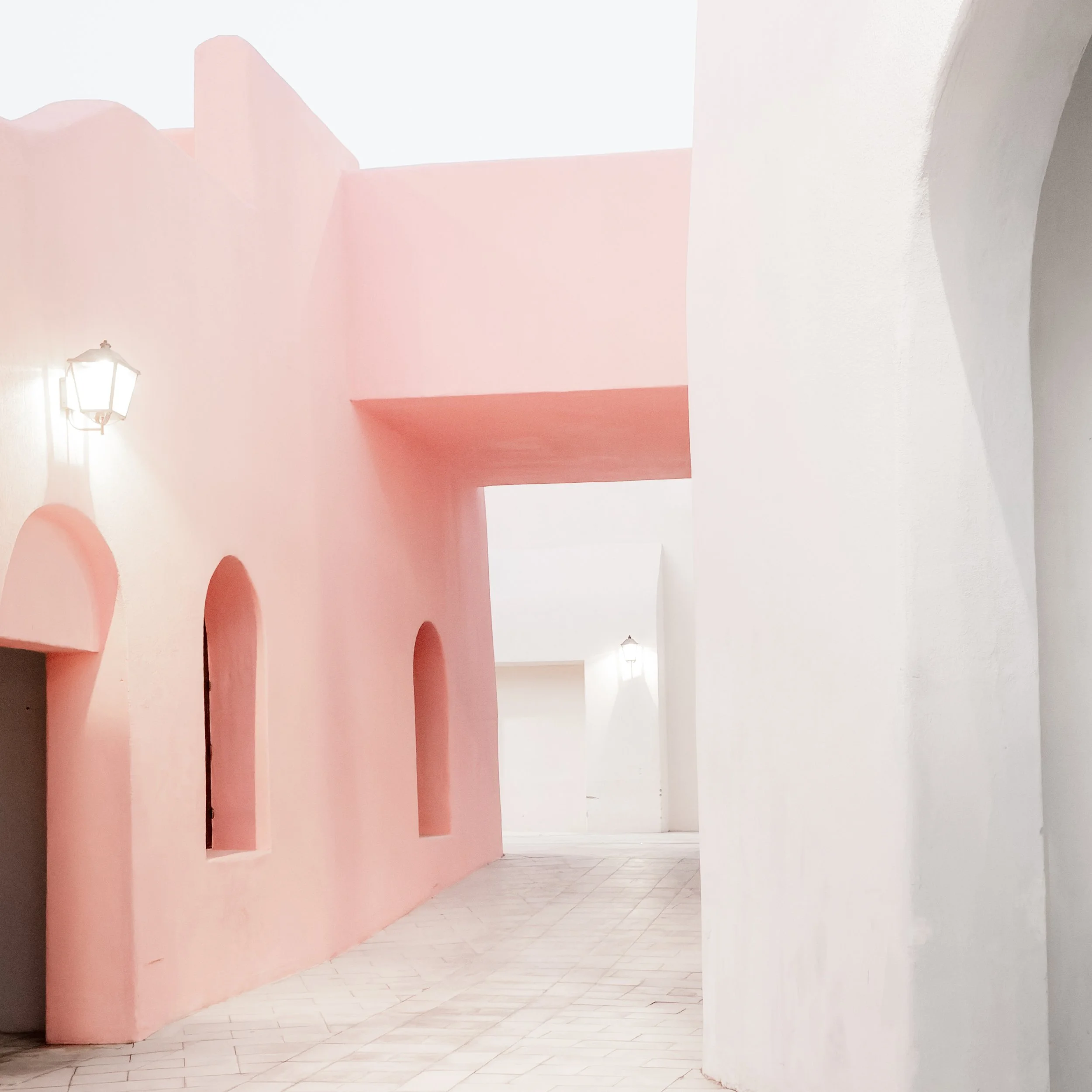Wooden pergola framing pastel alley in Mina District, Doha, with West Bay skyline in the background.