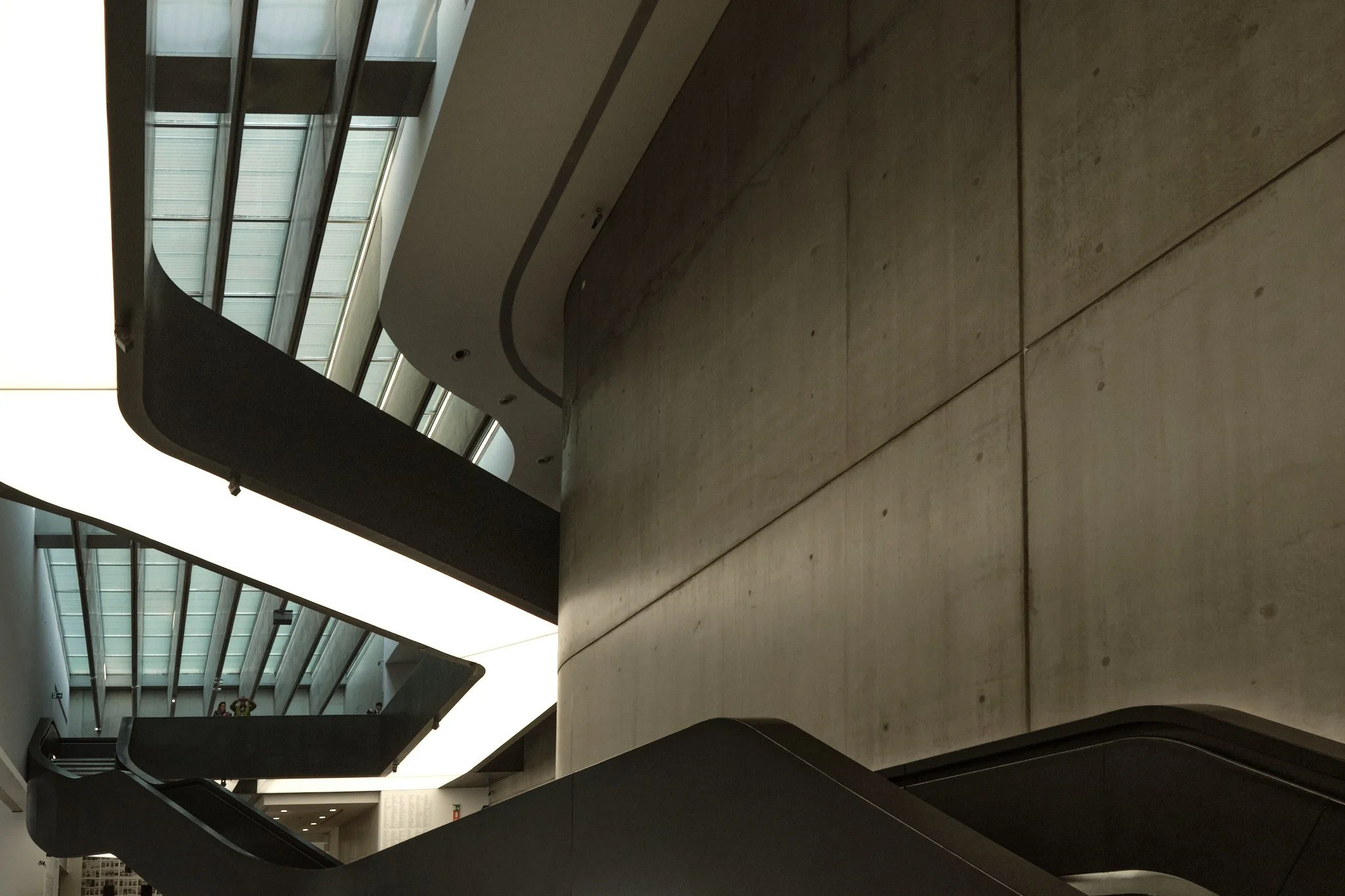 Interior staircase at MAXXI Rome with natural light entering from a lateral aperture, concrete and light in direct exchange.
