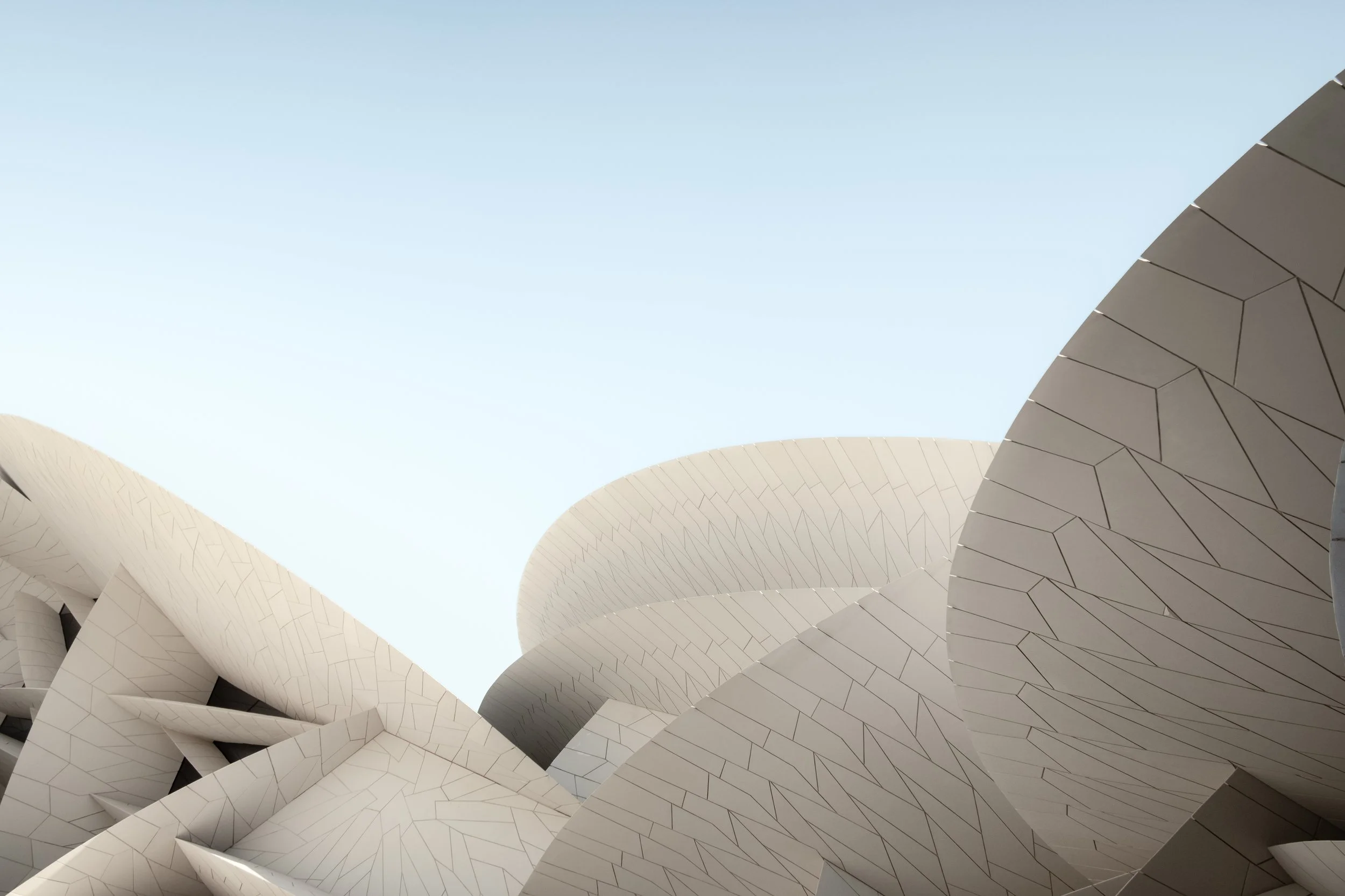 Architectural detail of the National Museum of Qatar in Doha, designed by Jean Nouvel, showing interlocking sand-colored discs inspired by desert rose formations under soft daylight.
