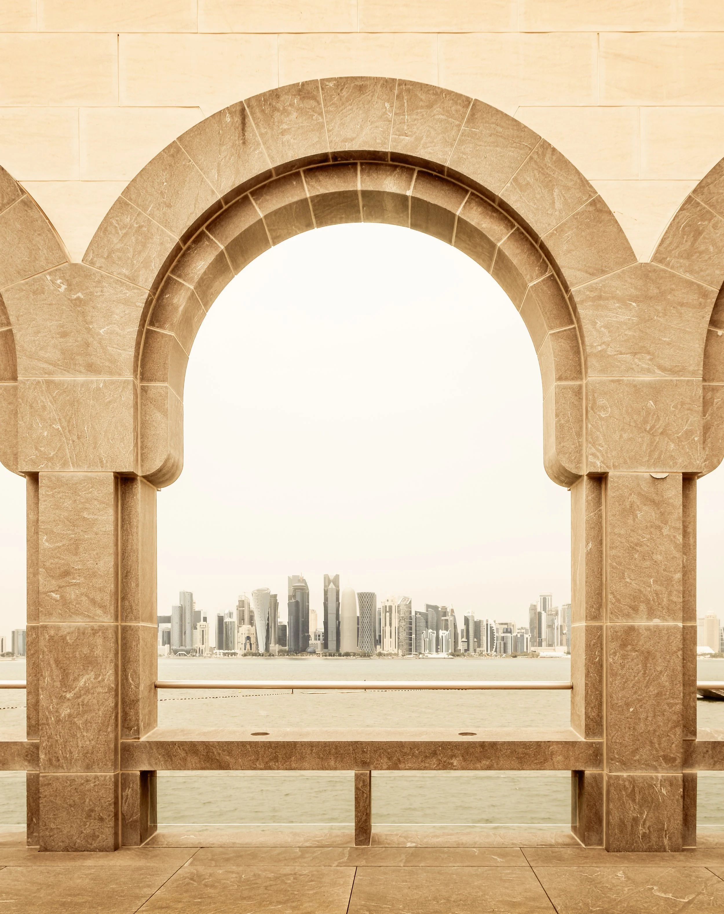 Doha skyline viewed through traditional stone arch at Museum of Islamic Art.