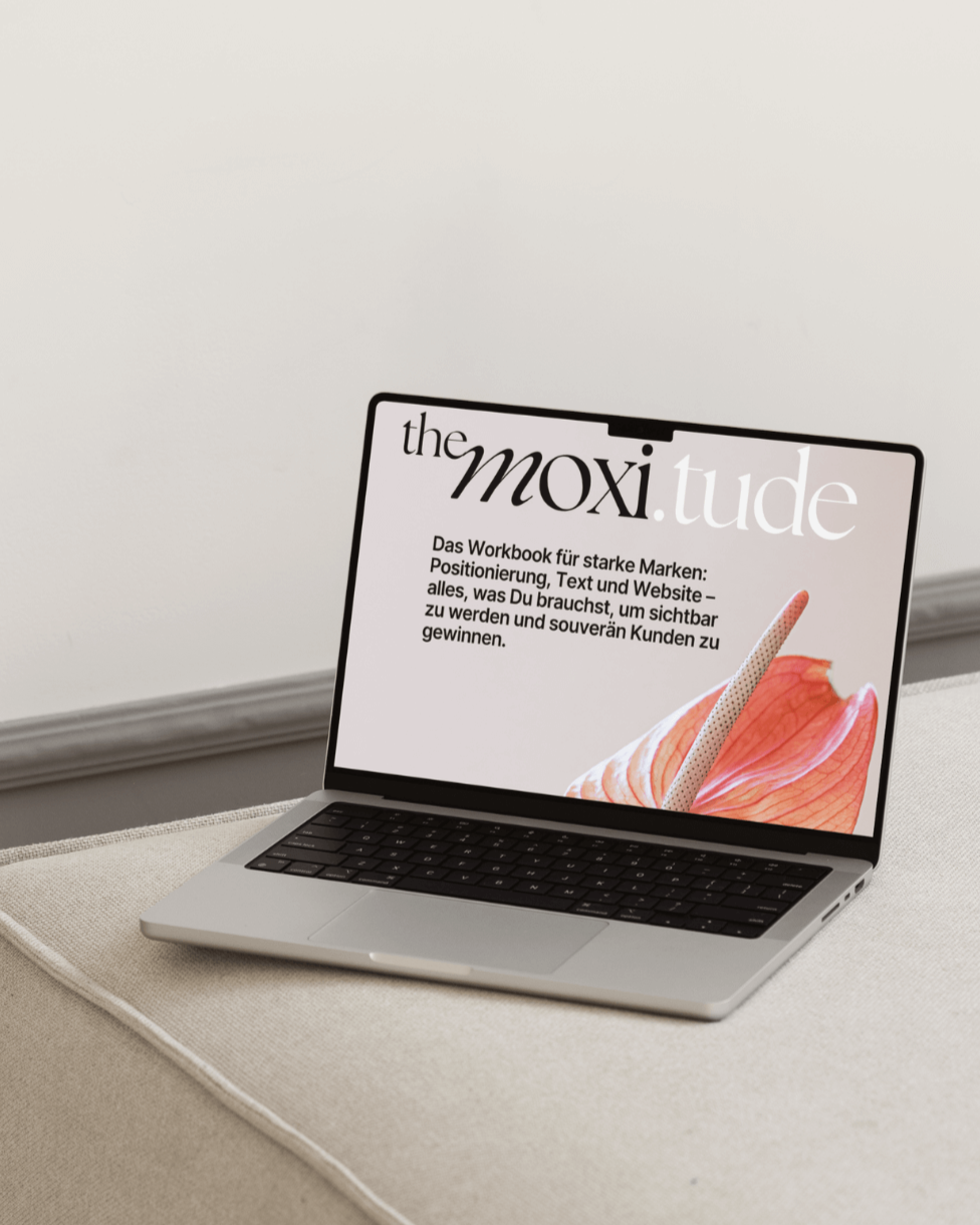 Ein Laptop auf einem Tisch zeigt eine Workbook mit dem Titel "the moxi.tude" und einem Blumendesign.