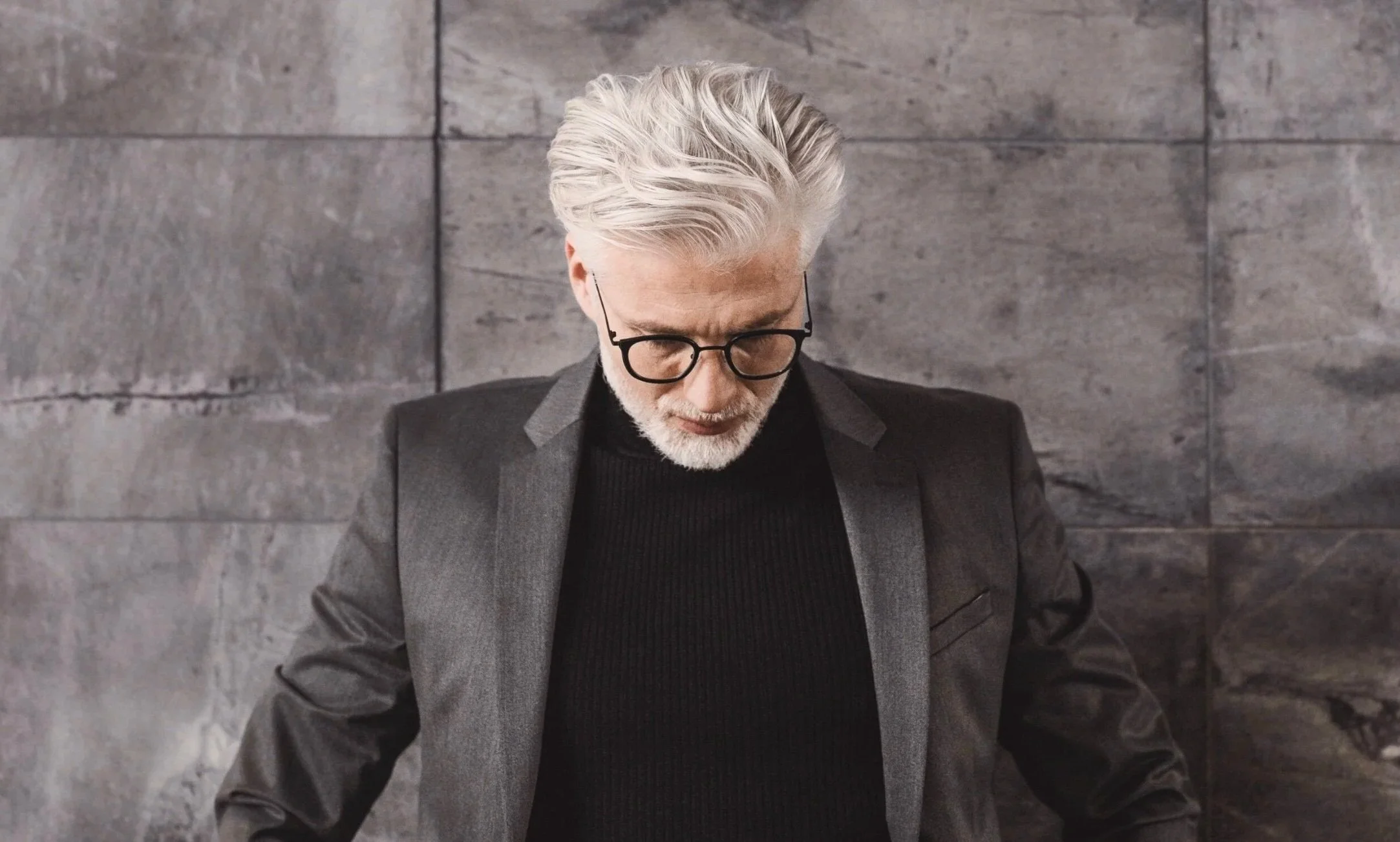 Mann im schwarze Pullover und grauem Jacket, Blick nach unten