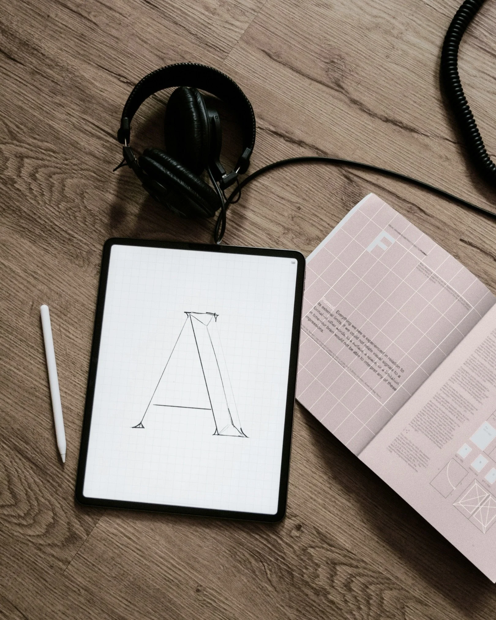 iPad auf Tisch mit dem Letter _A und  daneben ein Buch, Gestaltung