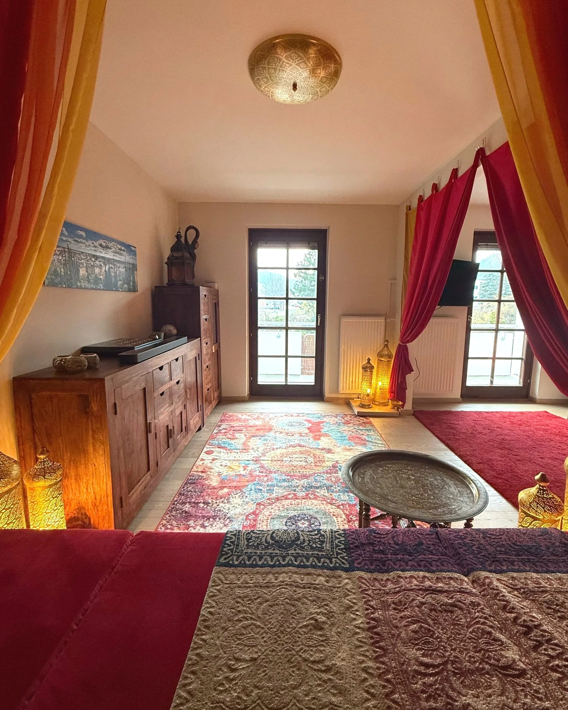 Vom Podest aus fällt der Blick zum Balkon und der Abendsonne; Es lädt zum lesen, entspannen und träumen ein unter dem Baldachin in rot, orange, gelb und blautönen.