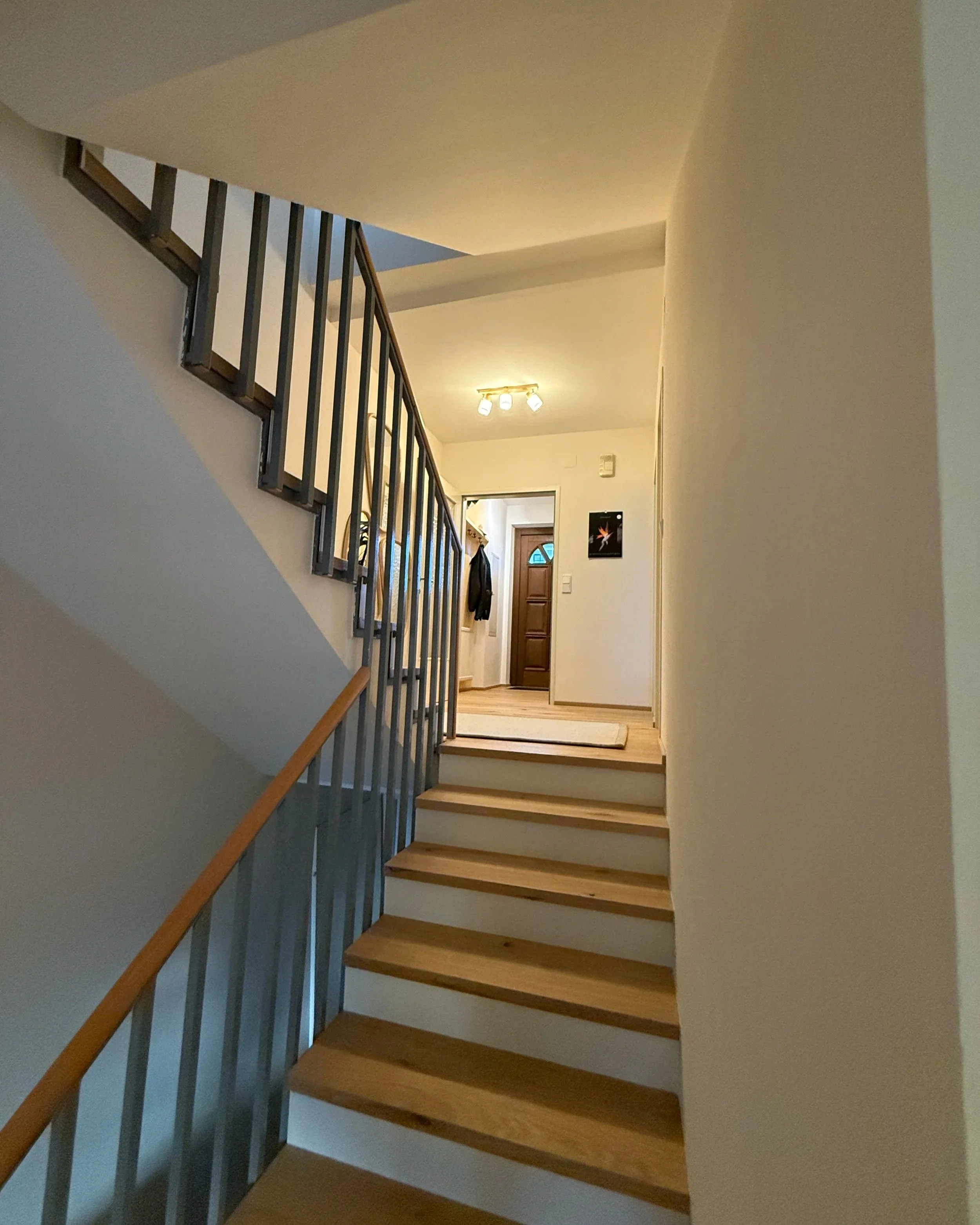 Der Stiegenaufgang wirkt nun warm - durch Parkett und cremefarbene Wände. Alles in allem wirkt der Flur freundlicher und ruhiger.