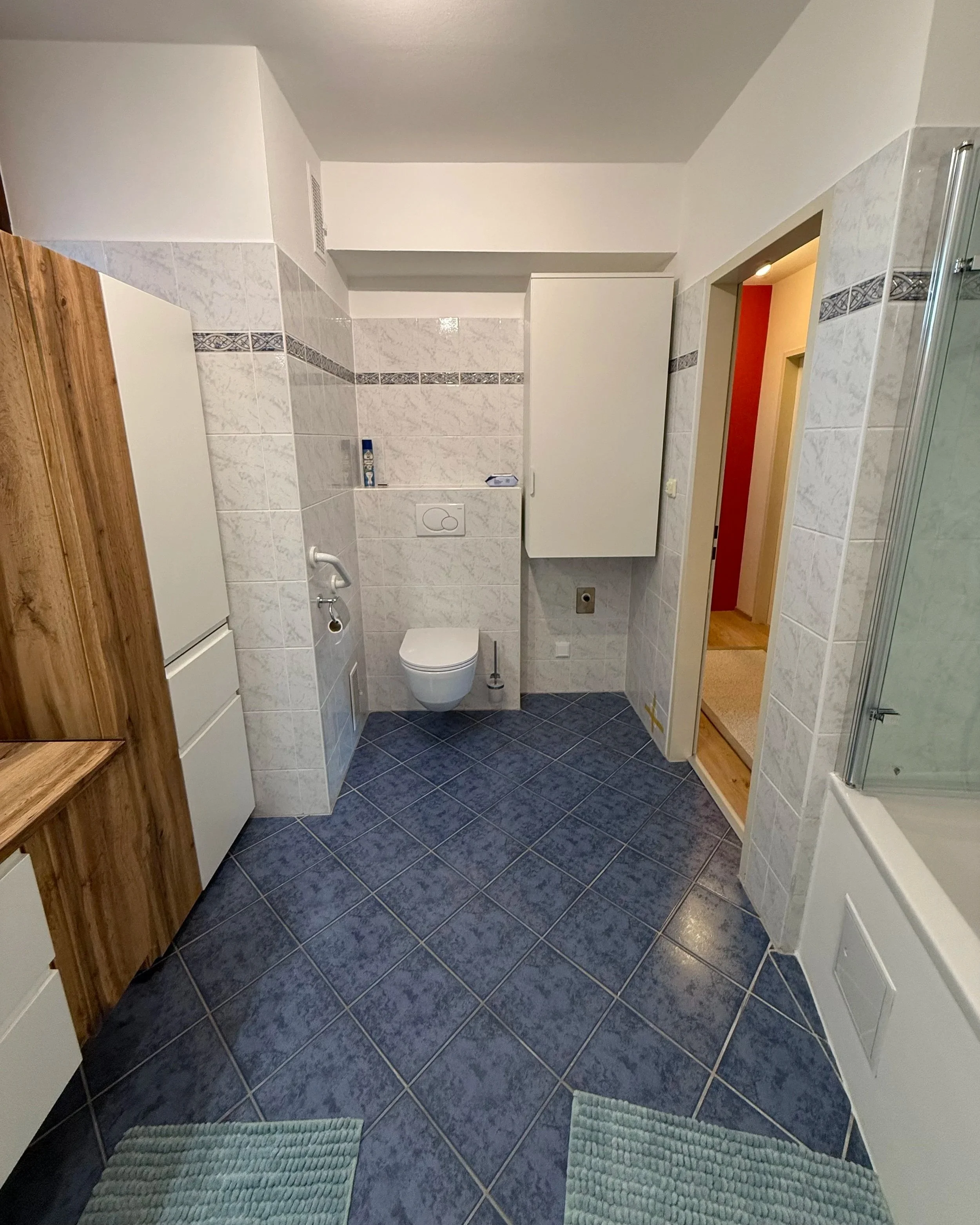 Durch die weißen Wandoberteile wirkt das Bad heller und reiner; die neuen Sanitäranlagen wie das WC geben eine Hygienische Oberfläche; Der Wäscheschrank über der Waschmaschine ist platzsparend und sinnvoll zugleich.