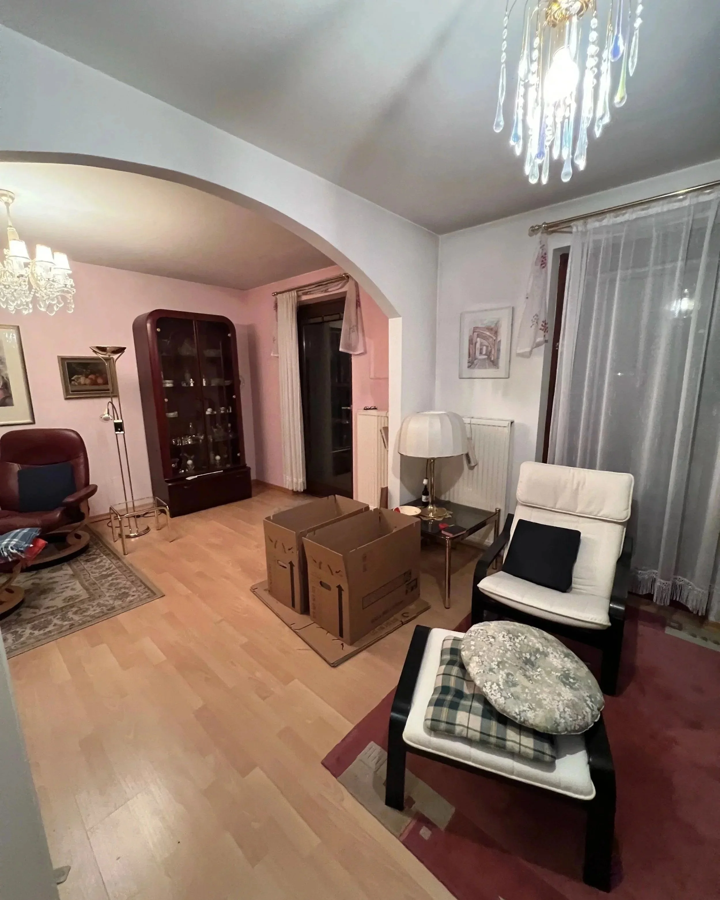 Vorraum Zwischengeschoss vor der Renovierung mit großer dunkler Schrankwand, dunkelrotem Teppich und Relaxsessel