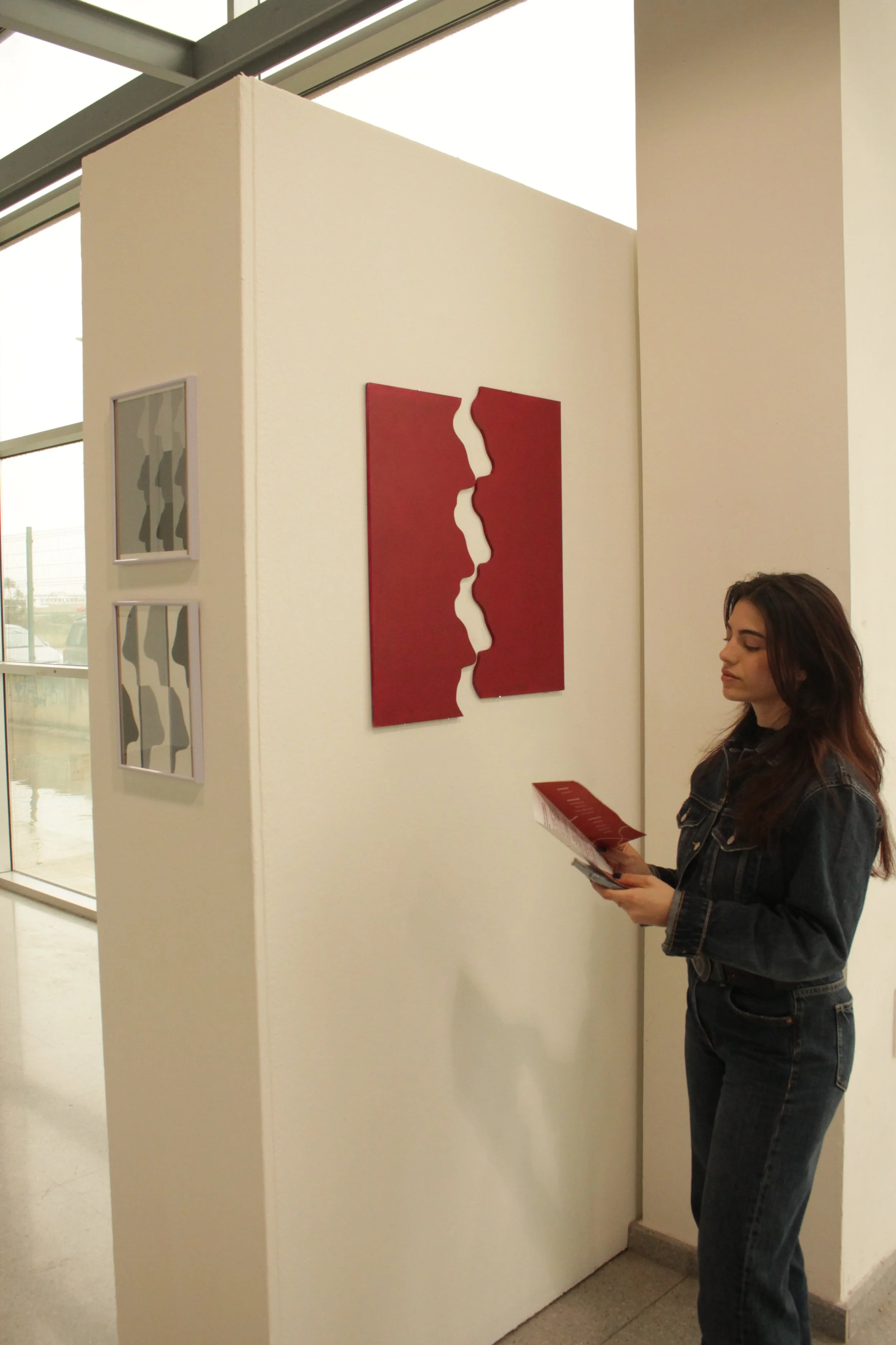 Mujer observando arte en una galería, con cuadros de formas abstractas en la pared.
