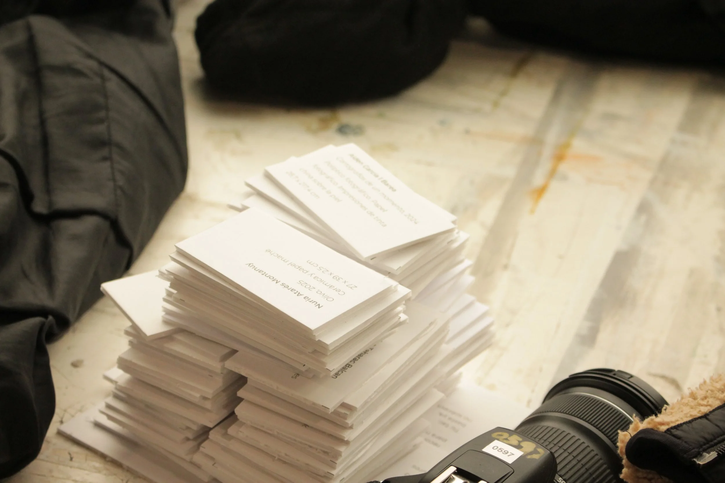 Montón de papeles y una cámara en una mesa de madera.