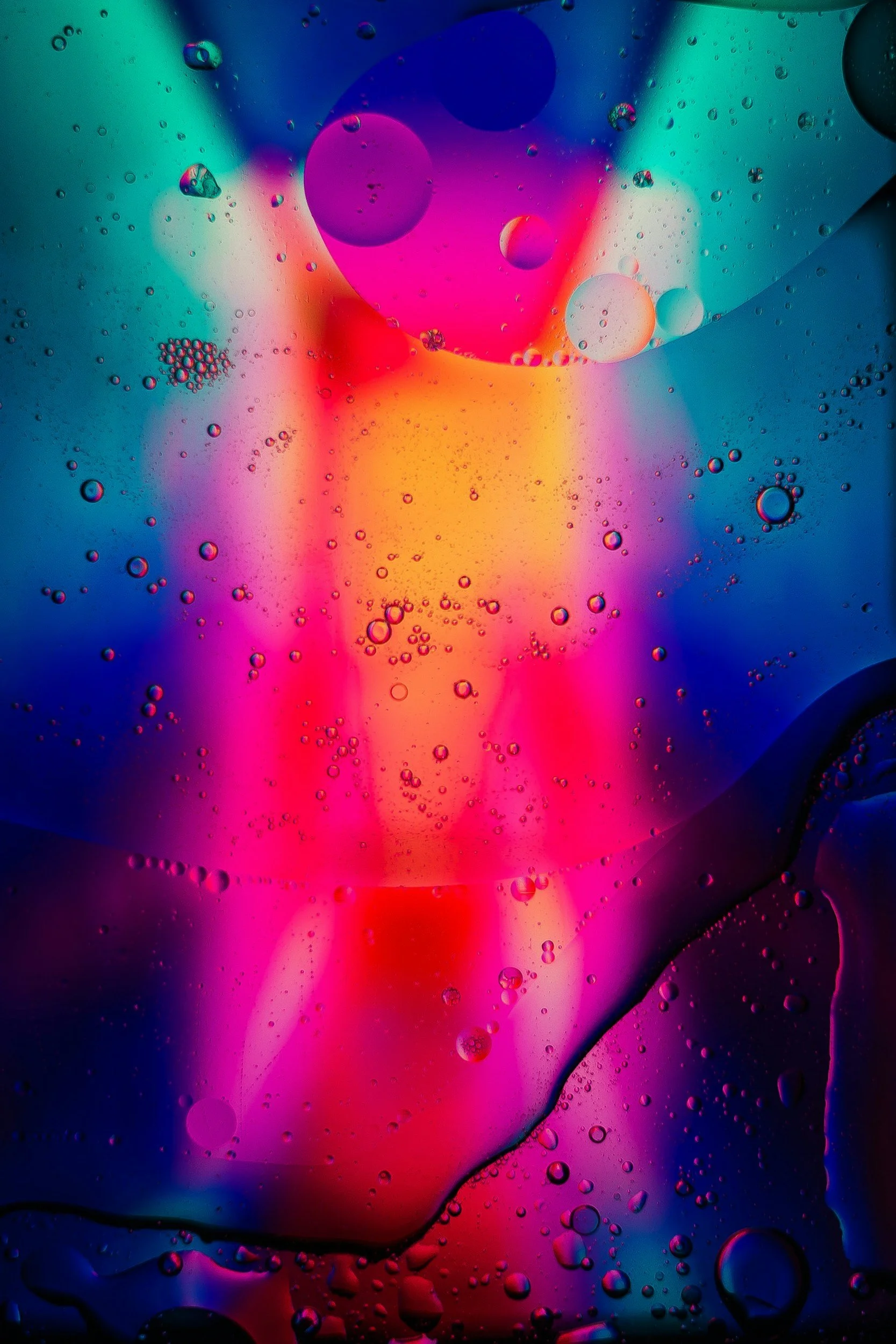 Abstract image of colorful oil droplets on water with pink, purple, blue, and yellow hues.
