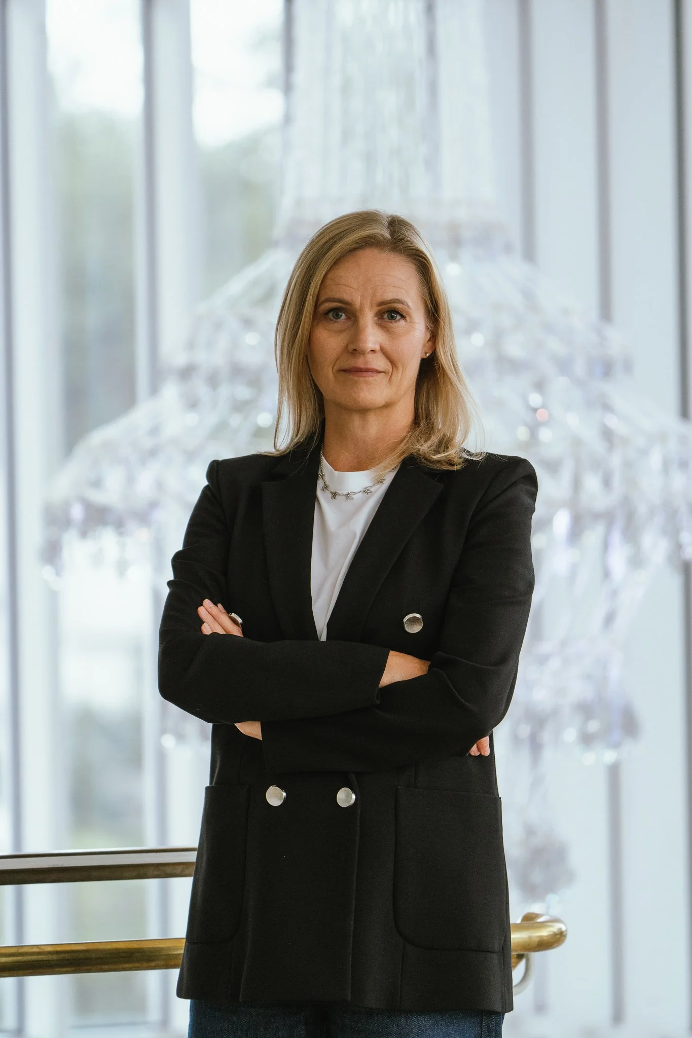 Nainen seisoo rinnan kohdalla ja katsoo suoraan kameraan.