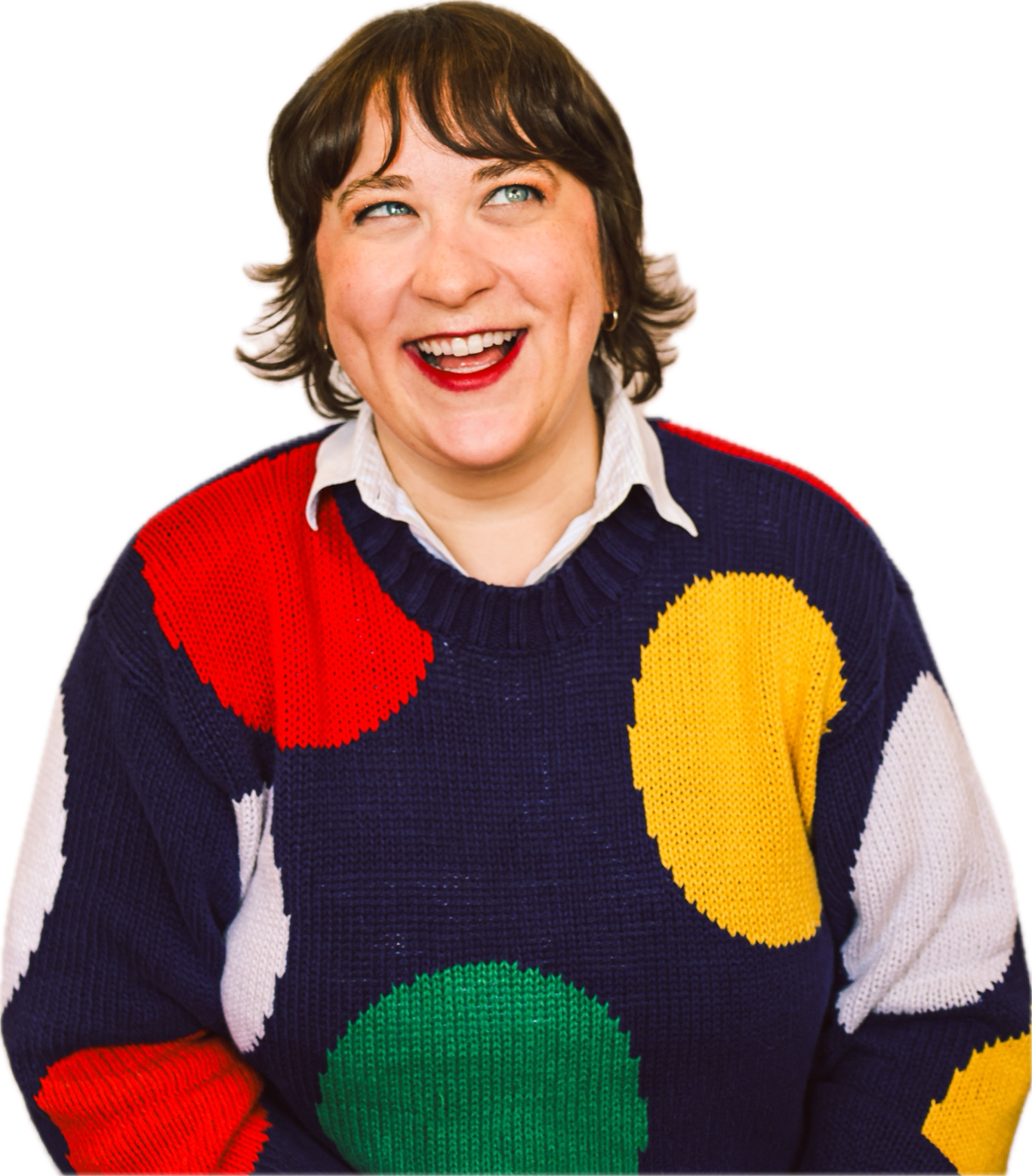 Woman with short brown hair smiling, wearing a colorful sweater with large polka dots in red, yellow, green, and white, over a white shirt.